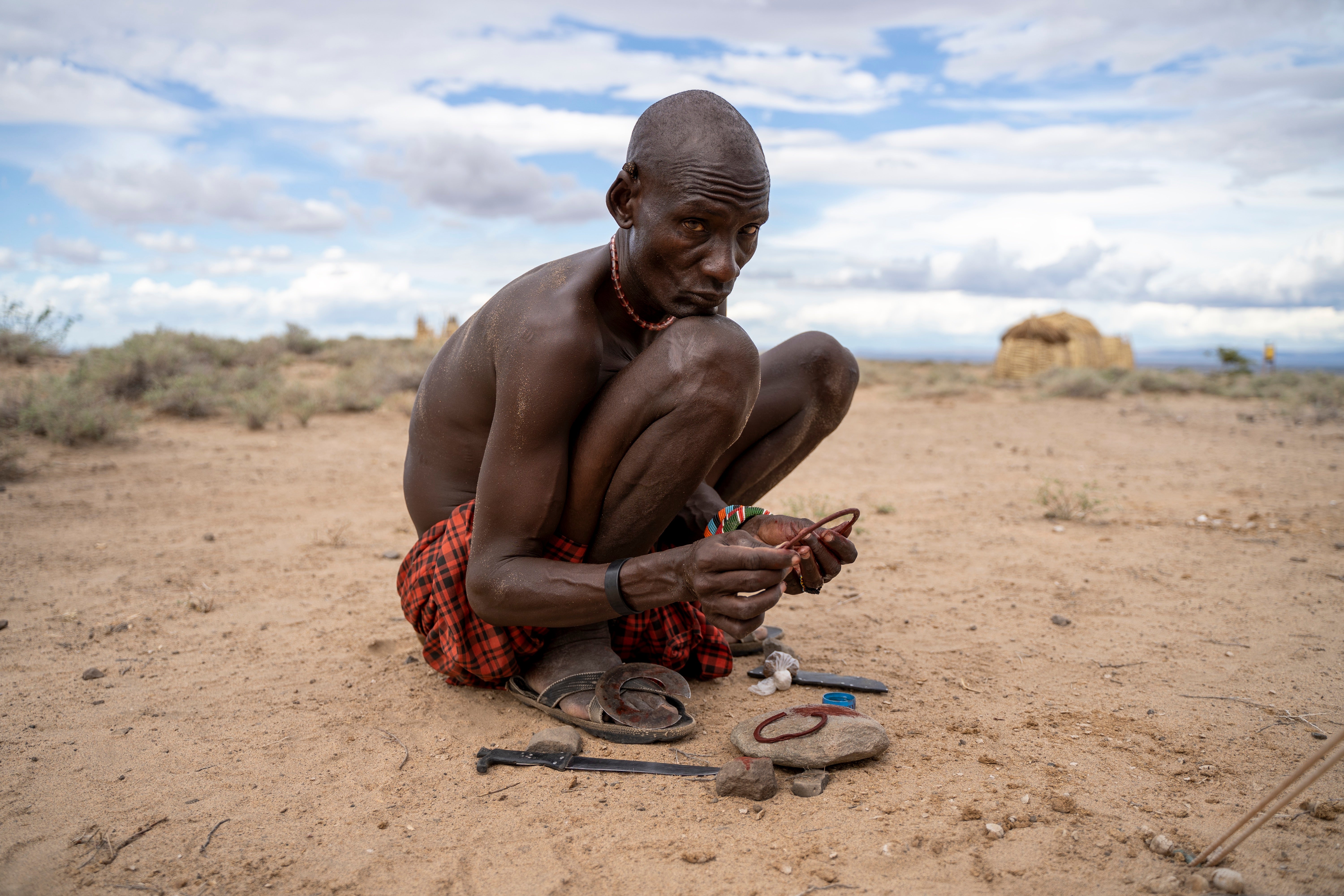 Loura Ekaale applying red ochre to the cowhide sheath of a circular wrist knife