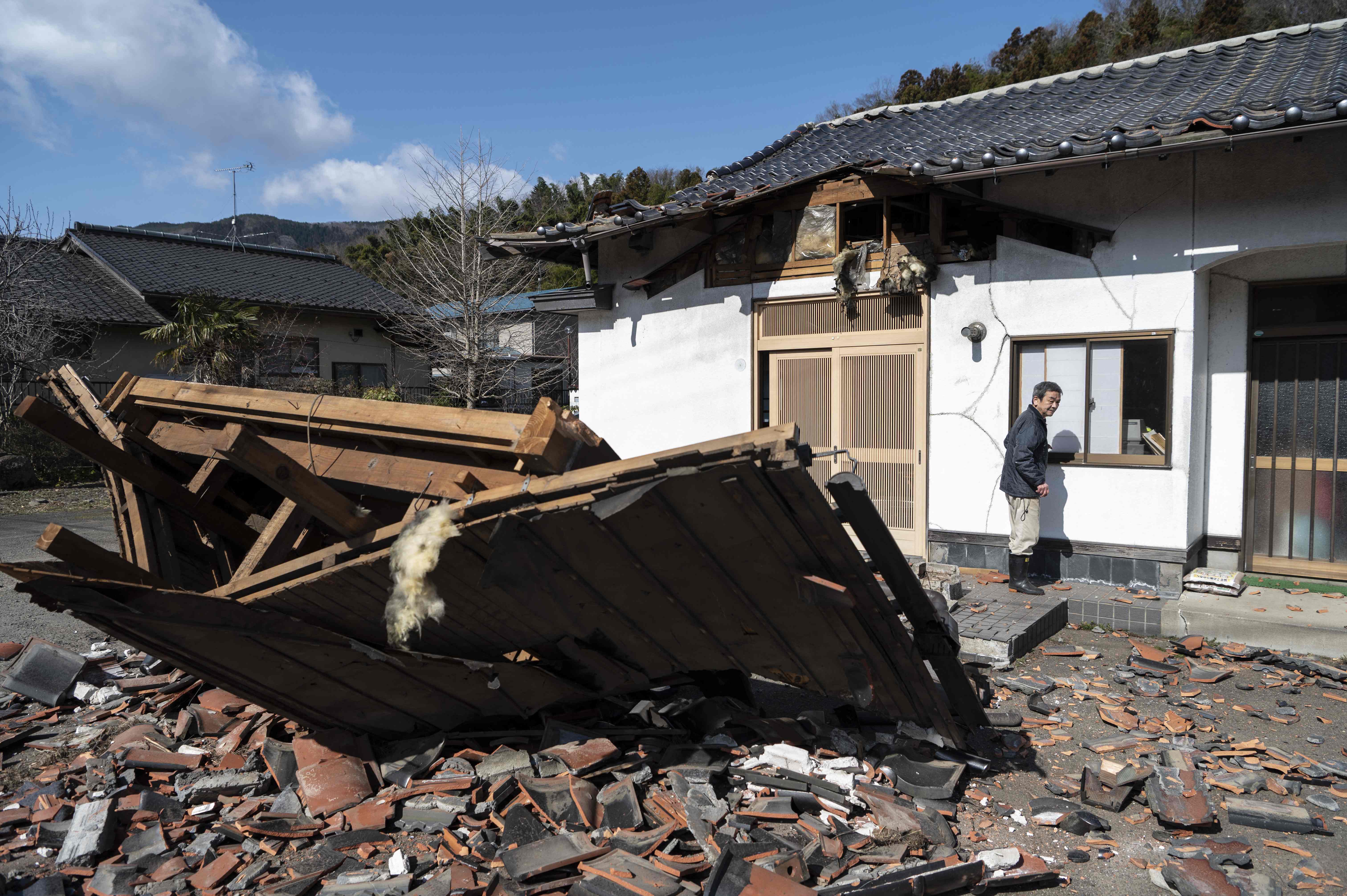 Sushi maker Akio Hanzawa walks in front of his damaged restaurant in Shiroishi, Miyagi prefecture