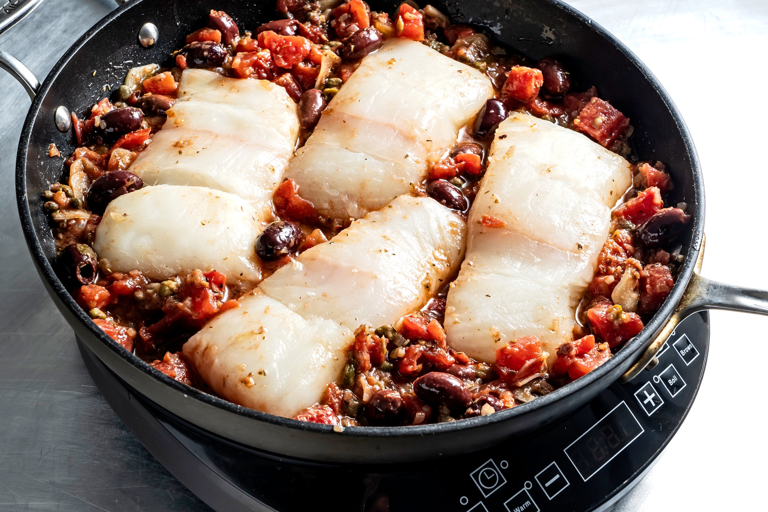 Halibut is nestled into the sauce and ready to go in the oven