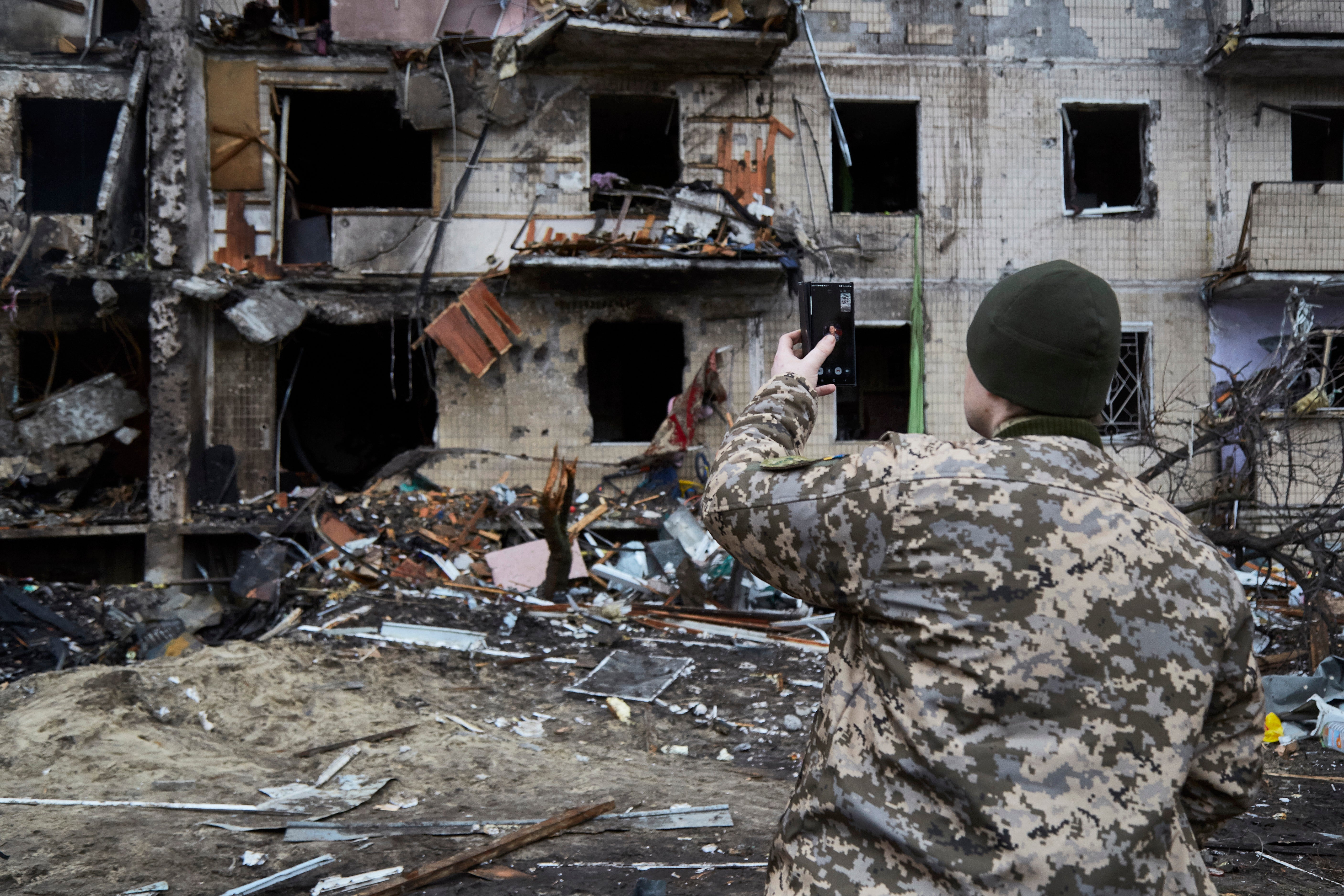 File photo: A Ukrainian soldier speaks on his smartphone outside a residential building damaged by a missile in Kyiv, Ukraine, 25 February 2022