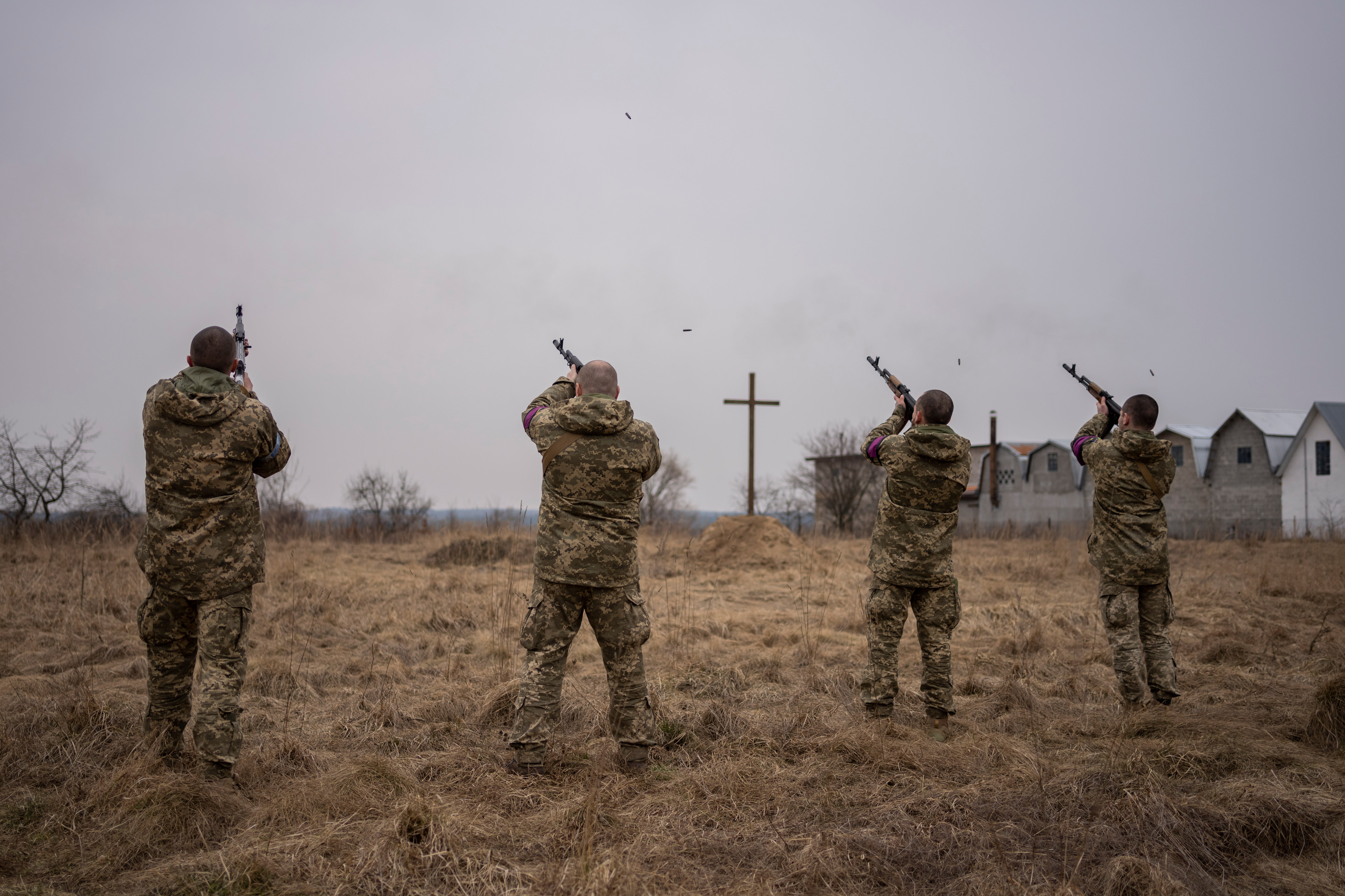 Ukrainian military servicemen fire salutes during the funeral of their comrades, Roman Rak and Mykola Mykytiuk, in Starychi, western Ukraine, Wednesday, March 16, 2022