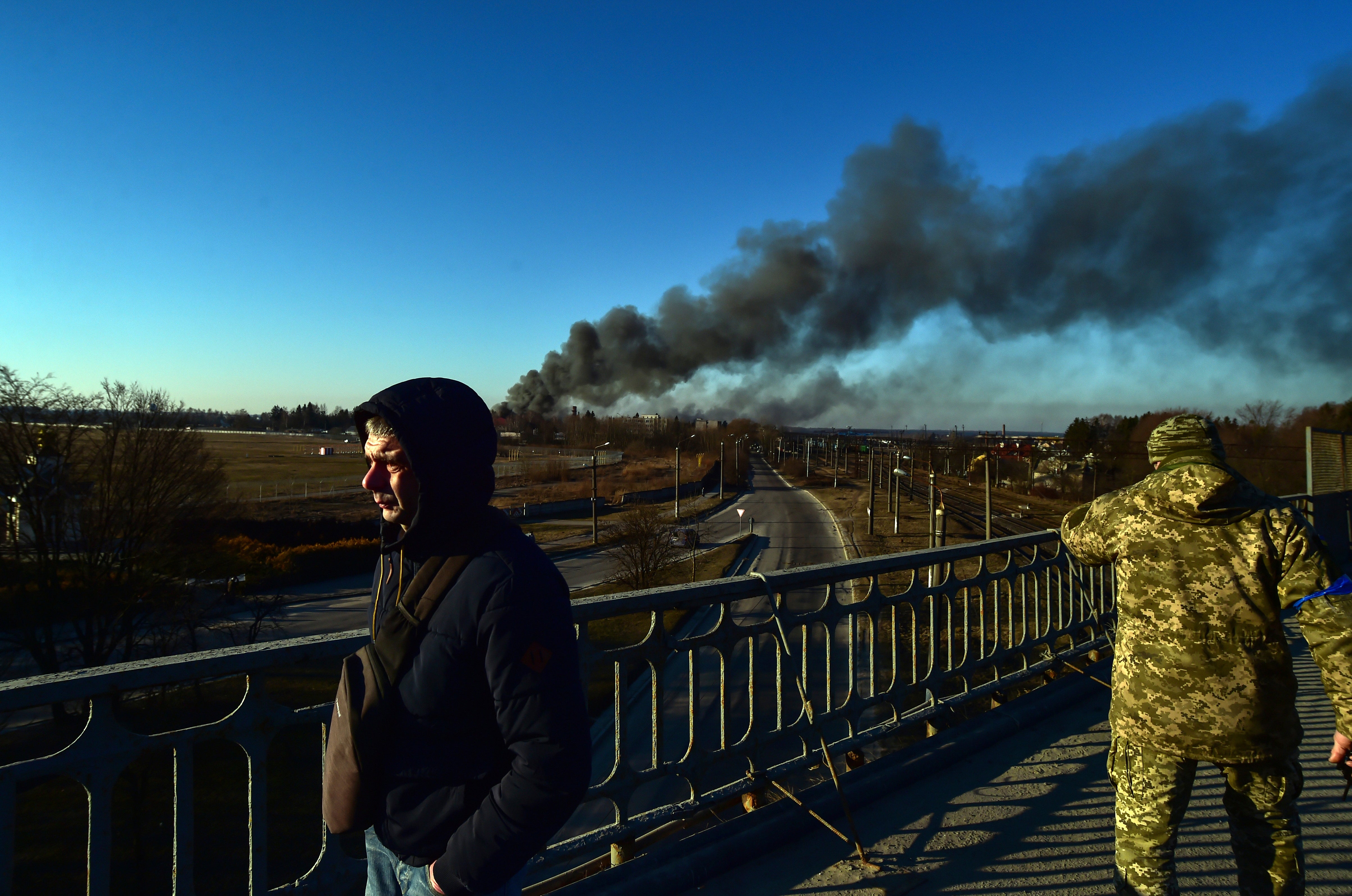 A Ukrainian soldier watches as smoke raises after an explosion near the airport, in Lviv, western Ukraine