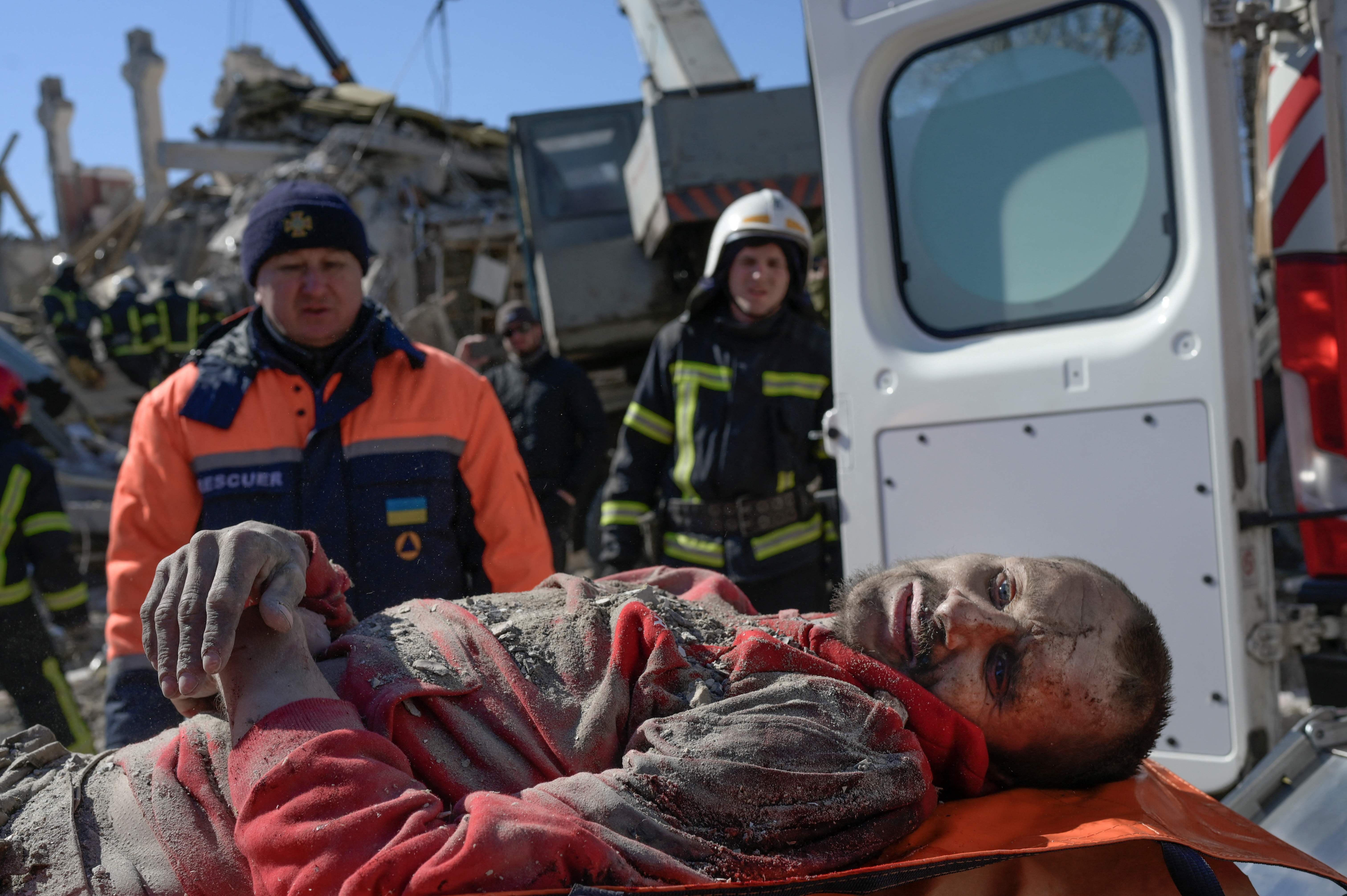 Rescuers carry a Ukrainian soldier saved after 30 hours beneath the debris of the military school hit by Russian rockets, in Mykolaiv