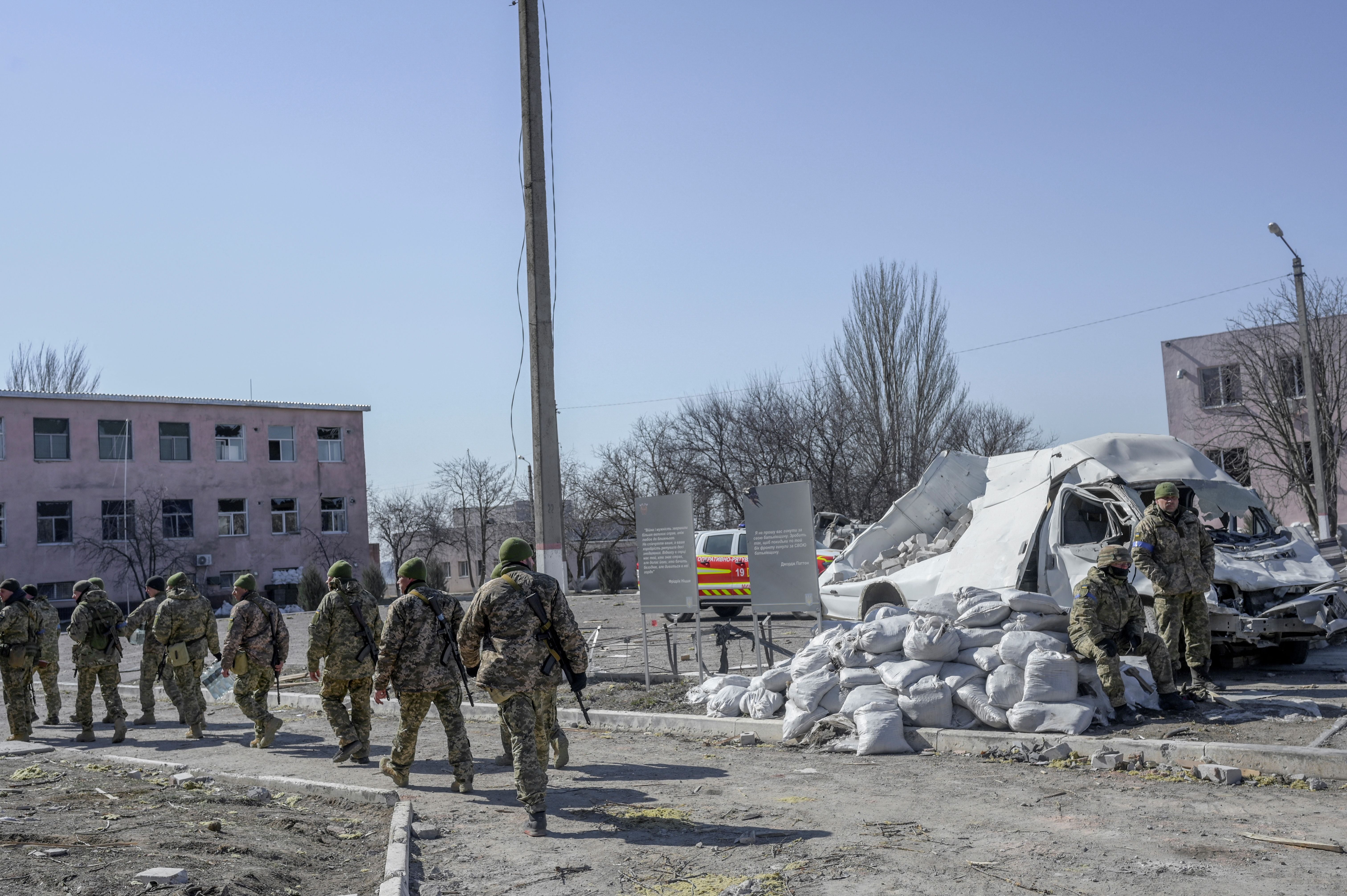 Ukrainian soldiers walk next to the military school hit by Russian rockets in Mykolaiv