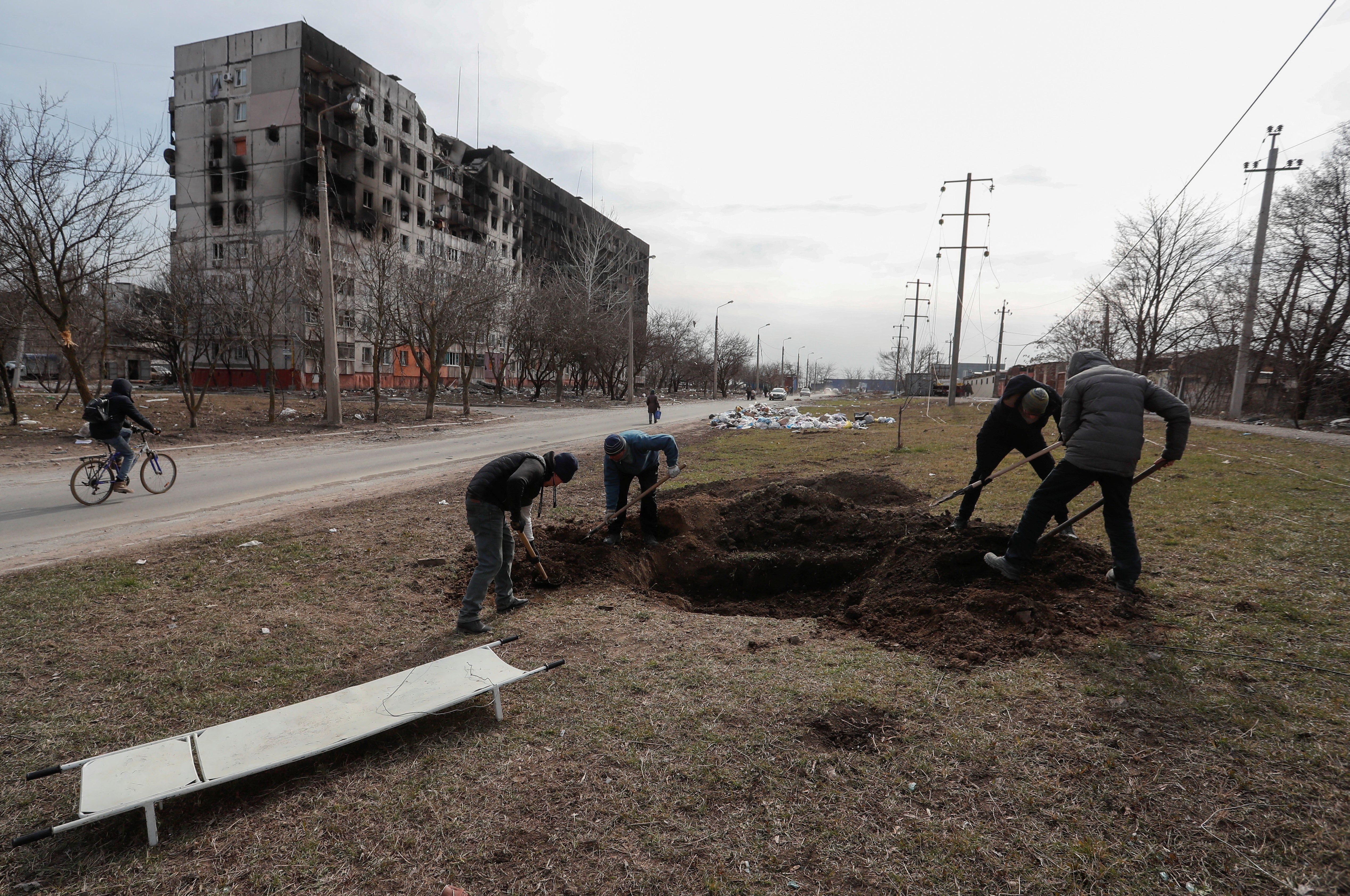 People dig a grave for victims killed during Ukraine-Russia conflict in a street in the besieged southern port city of Mariupol