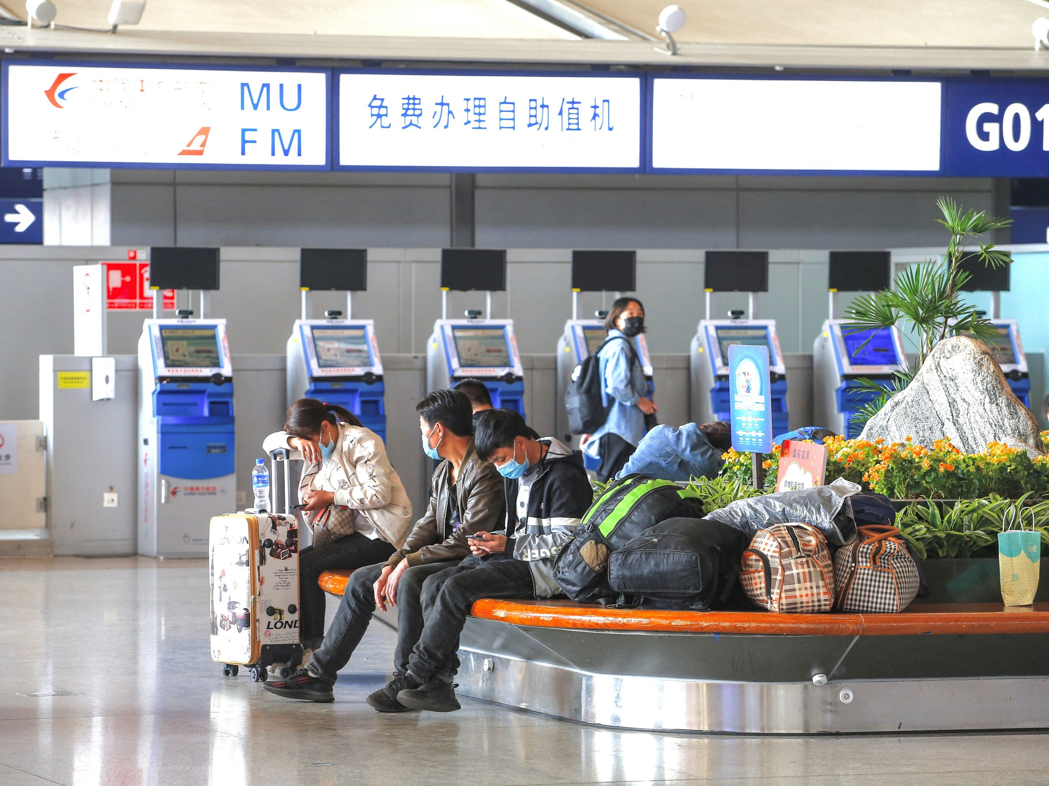 Passengers sit in front of the self-service machines of China Eastern Airlines at Changshui International Airport after the crash