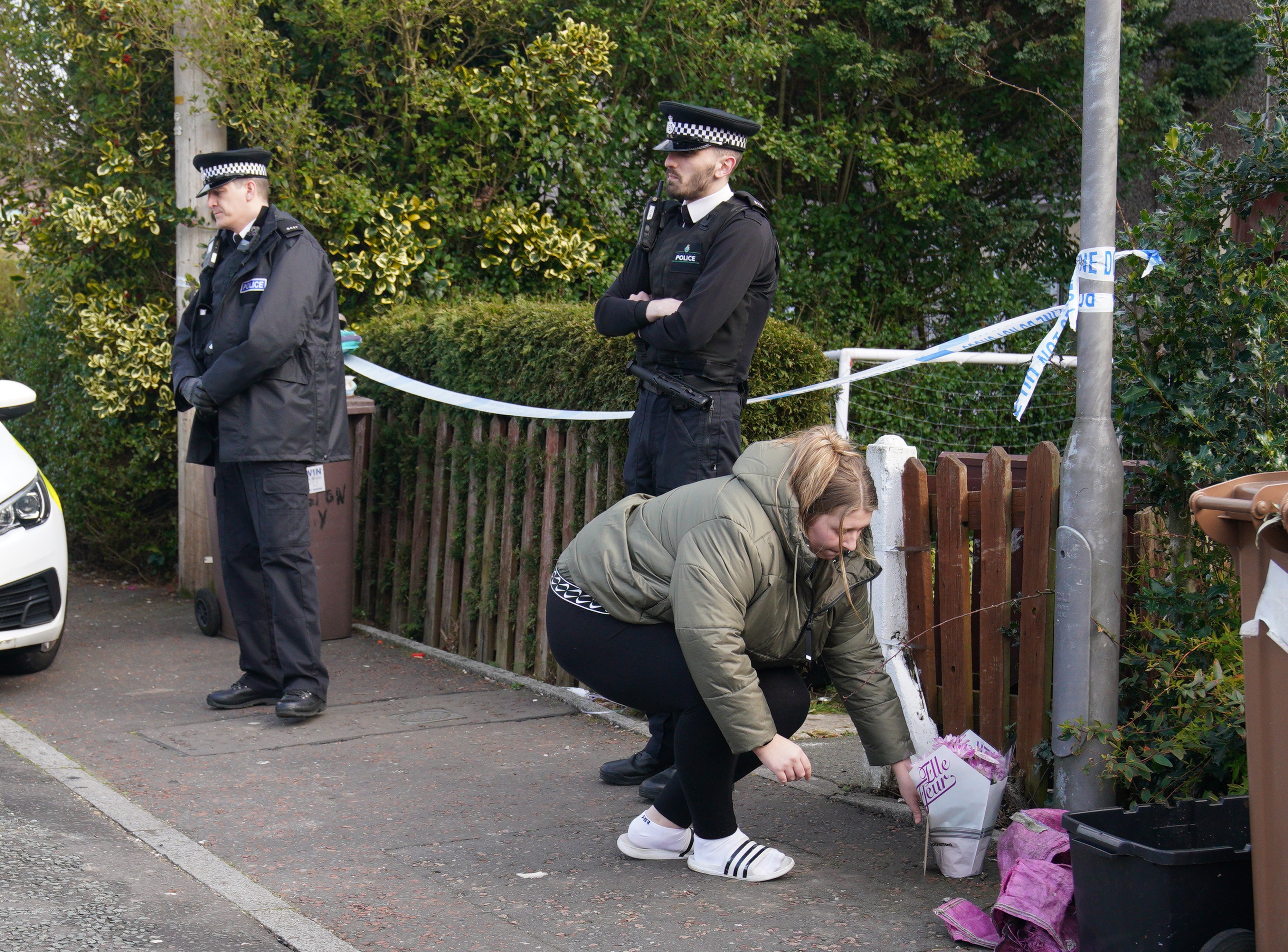 A woman lays flowers at the house in St Helens after the attack (Peter Byrne/PA)