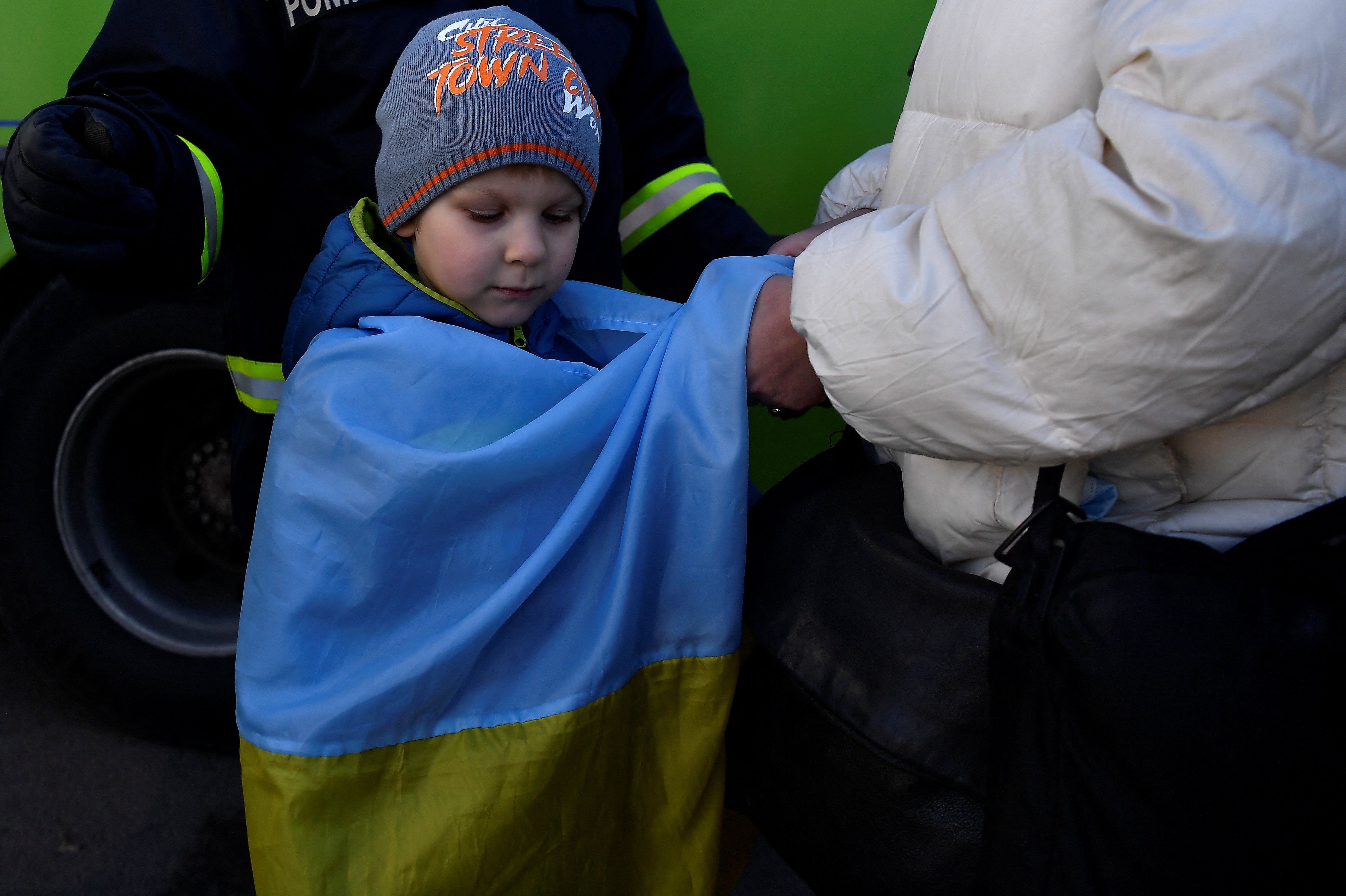 Ivan Iustushenko, 5, is wrapped in a Ukrainian flag by his grandmother after fleeing from Mariupol in Ukraine to Romania, following Russia's invasion of Ukraine, at the border crossing in Siret, Romania