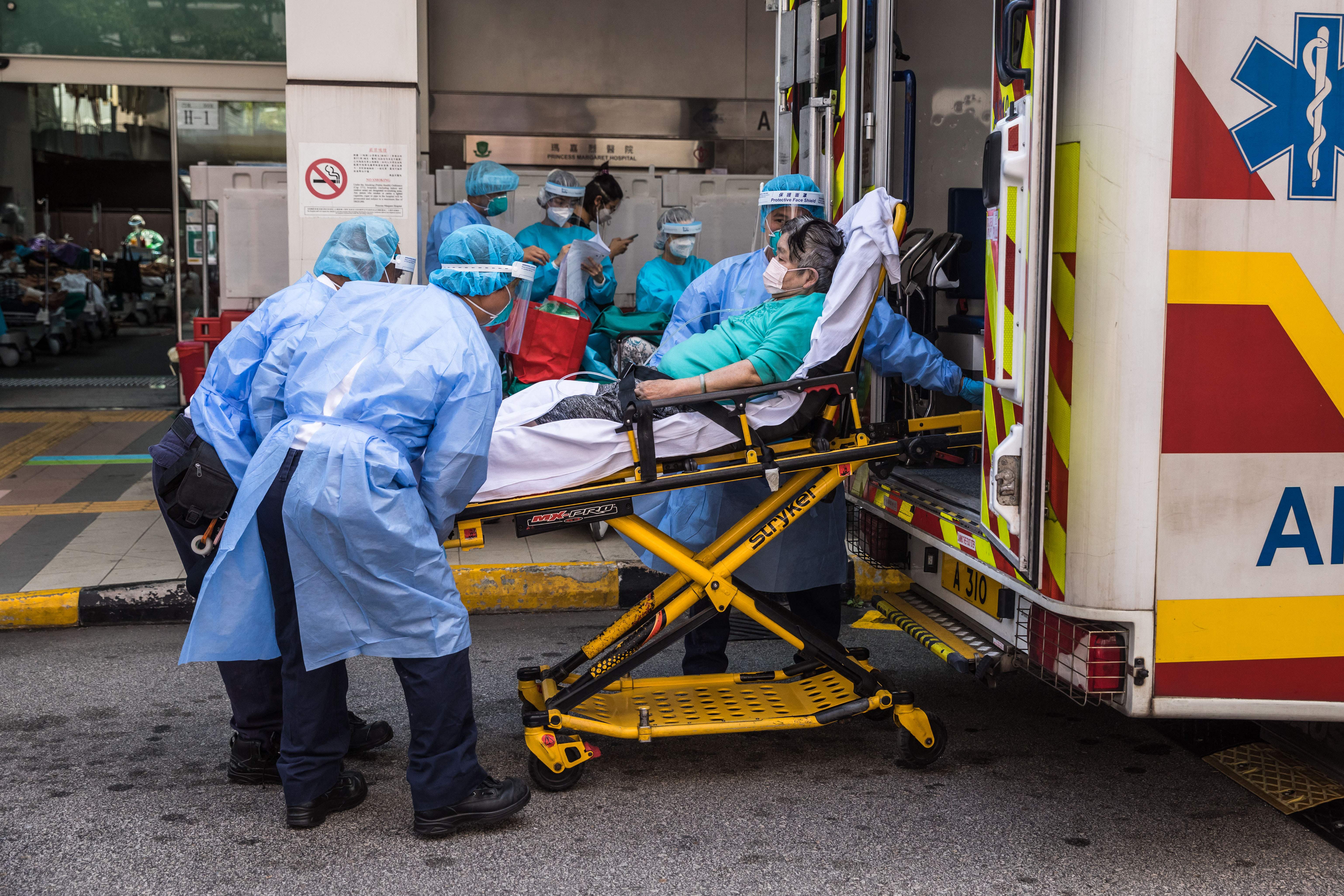 Health workers in PPE unload a patient from an ambulance outside the A&E department of Princess Margaret hospital in Hong Kong, 11 March 2022