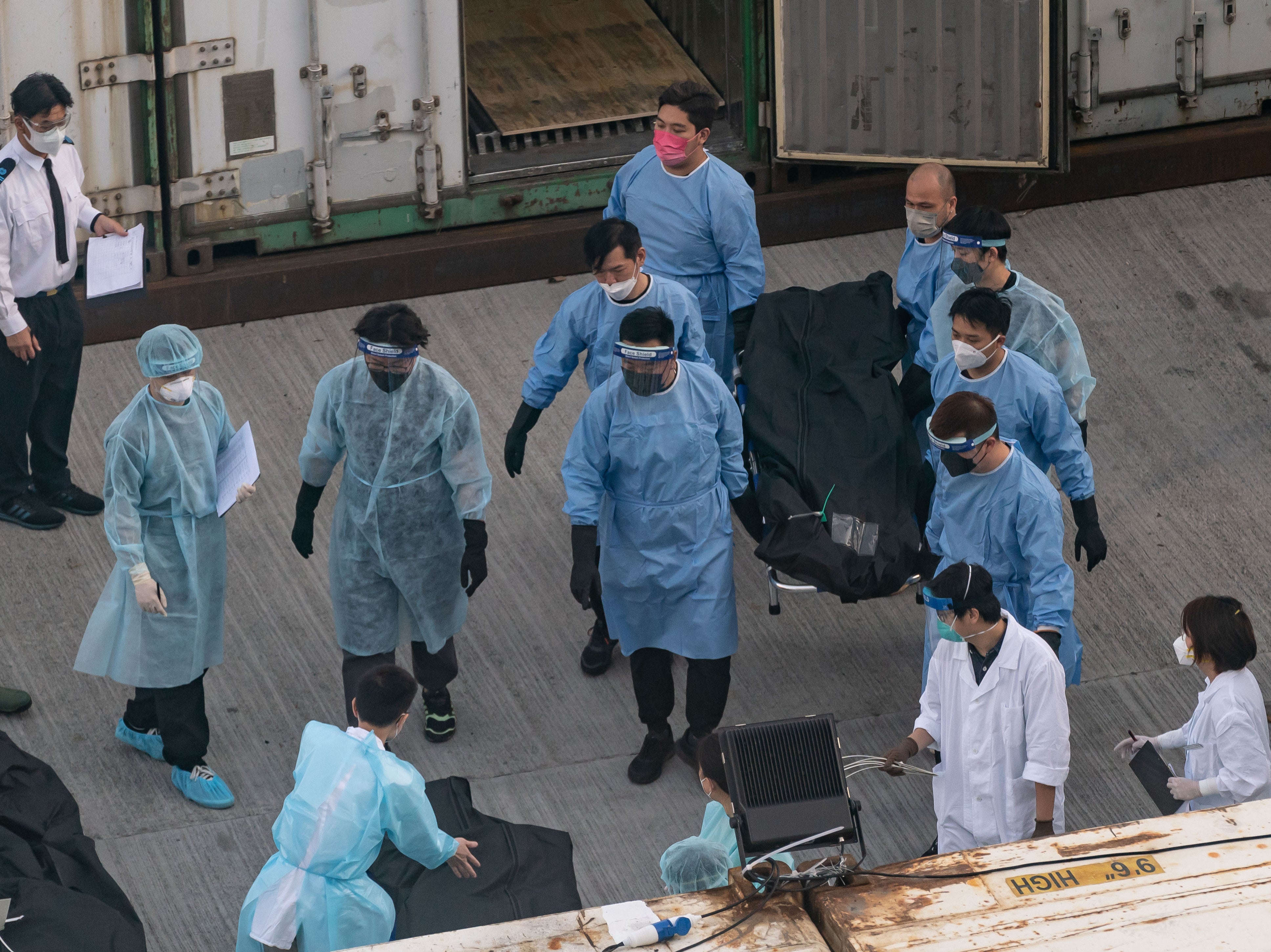 Workers transfer the body of a deceased person at a mortuary in Hong Kong, 7 March 2022