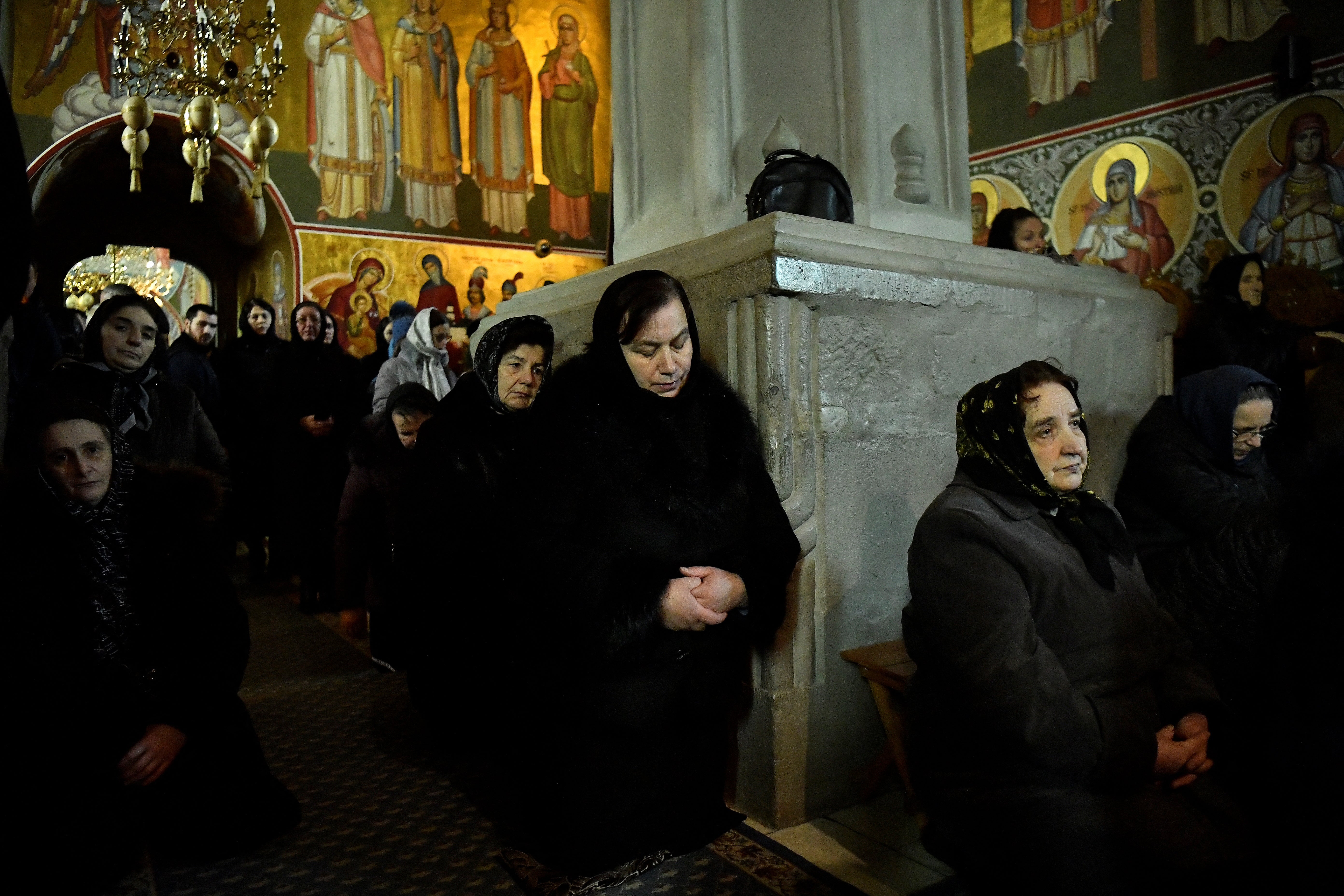 Local people pray during mass in the church at Putna monastery