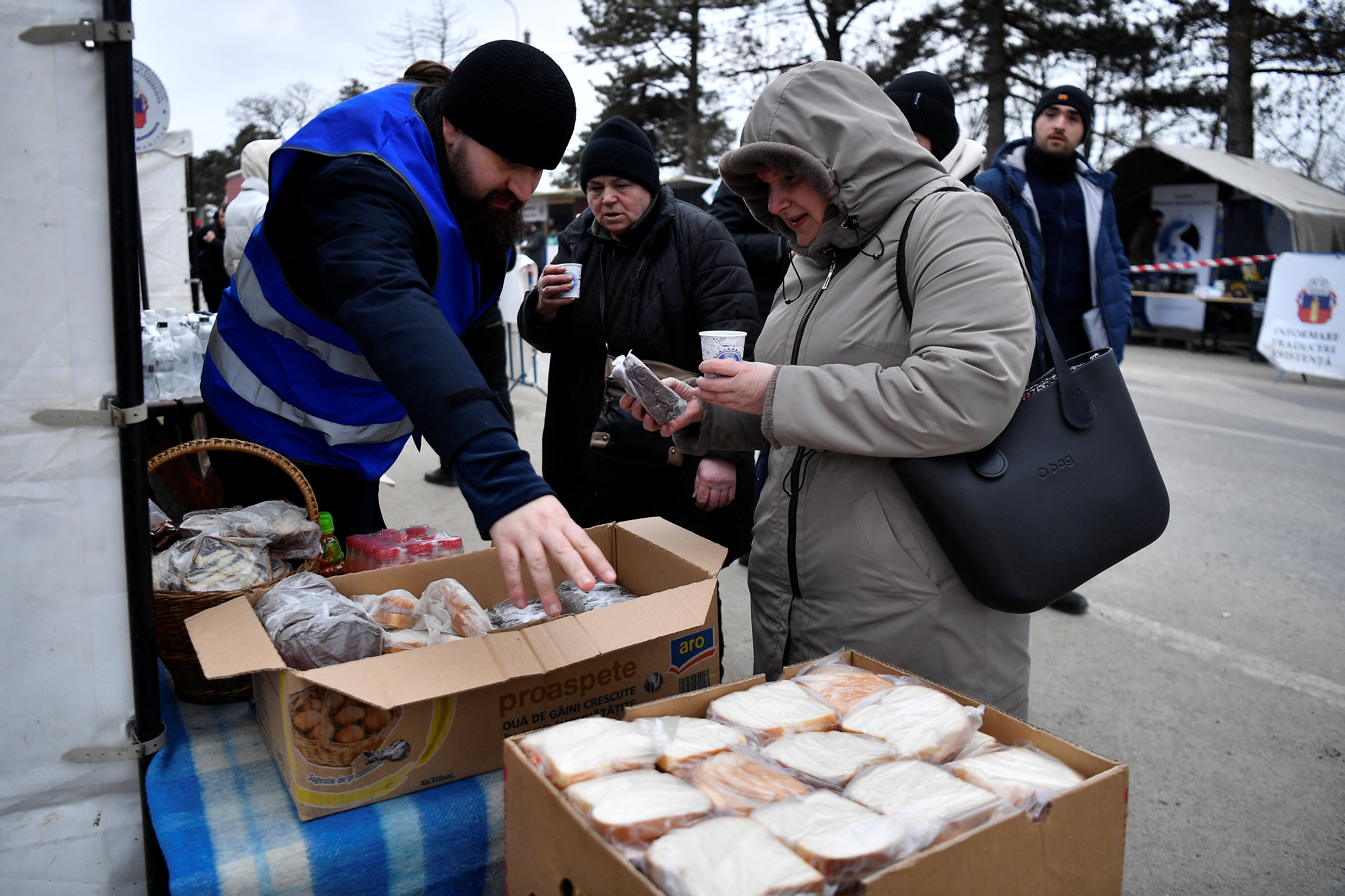 Father Mikhail offers Ukrainian refugees food at their hospitality tent in Siret