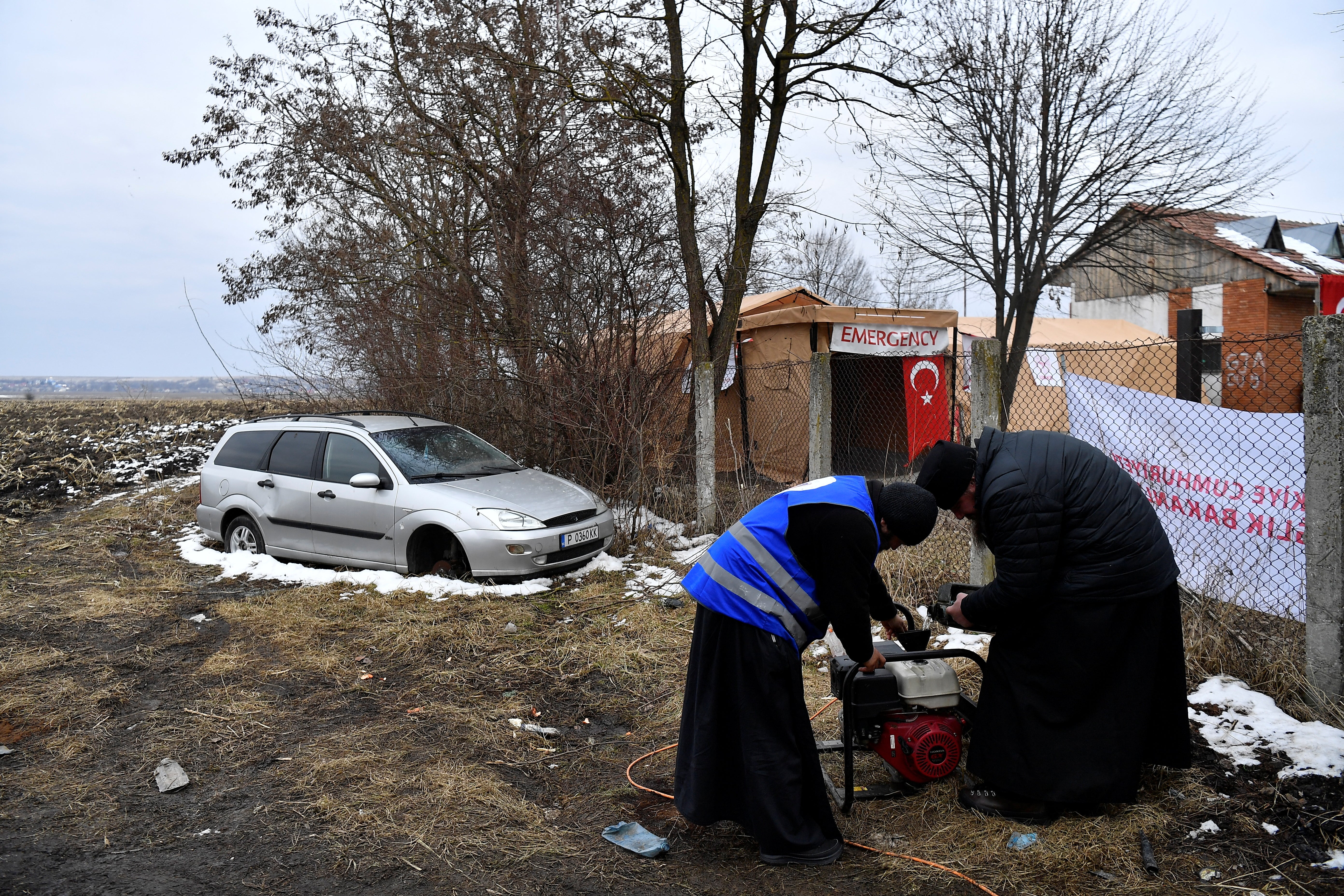 Father Calinic and Father Modest work to fix a generator beside their hospitality tents in Siret