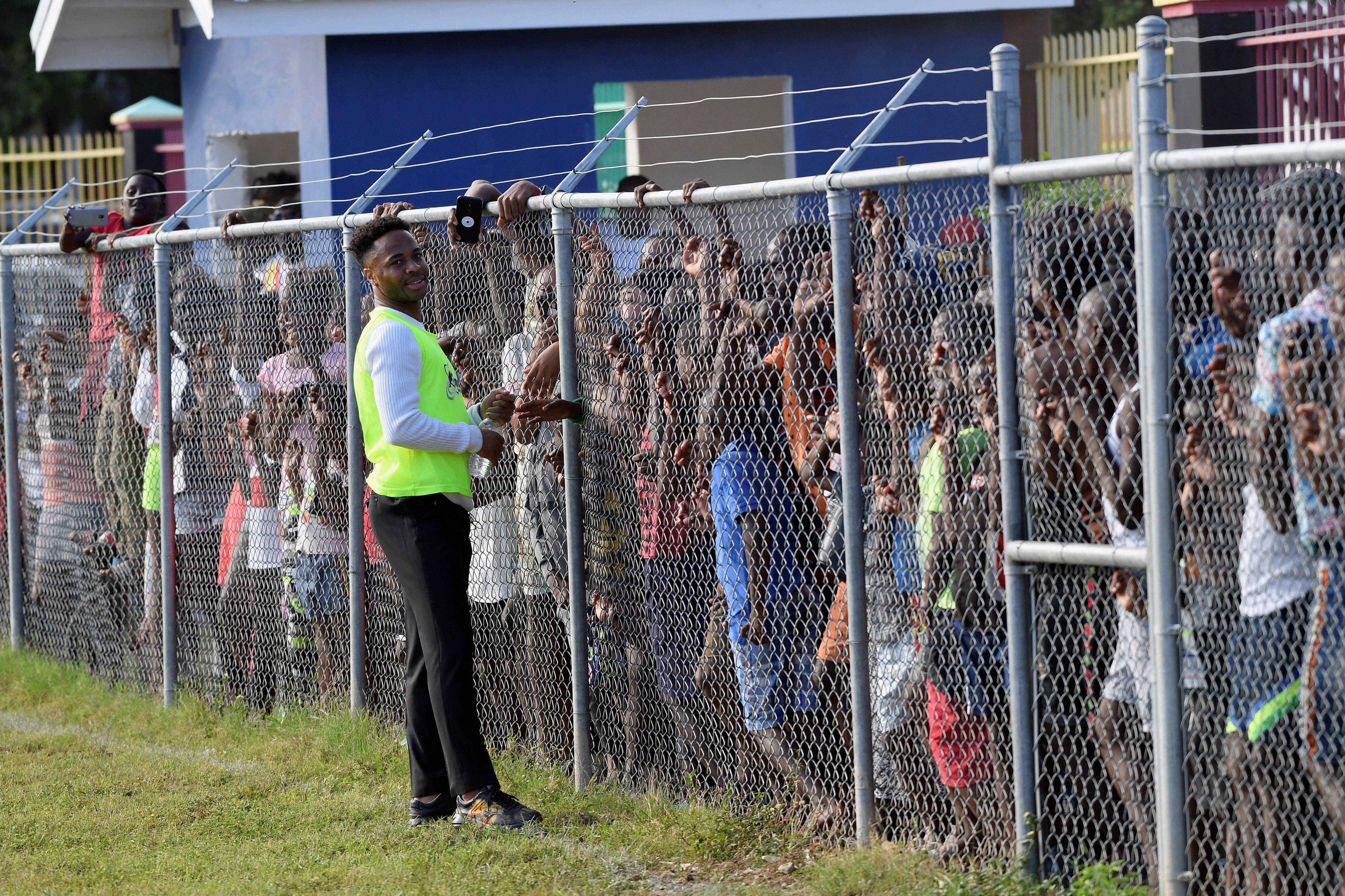 Raheem Sterling of Manchester City looks on while talking with people waiting for the arrival of Prince William