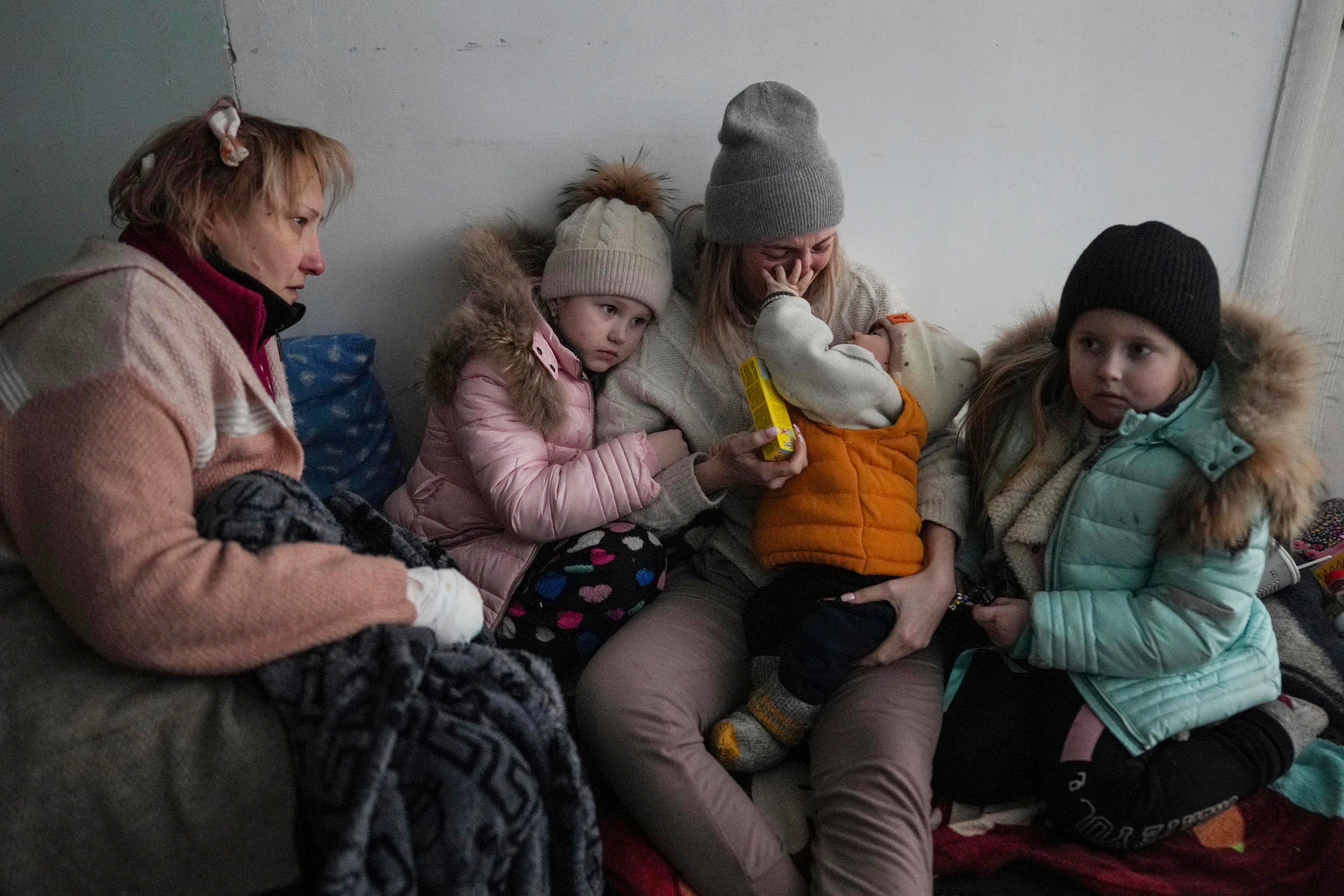 Women and children sit on the floor of a corridor in a hospital in Mariupol