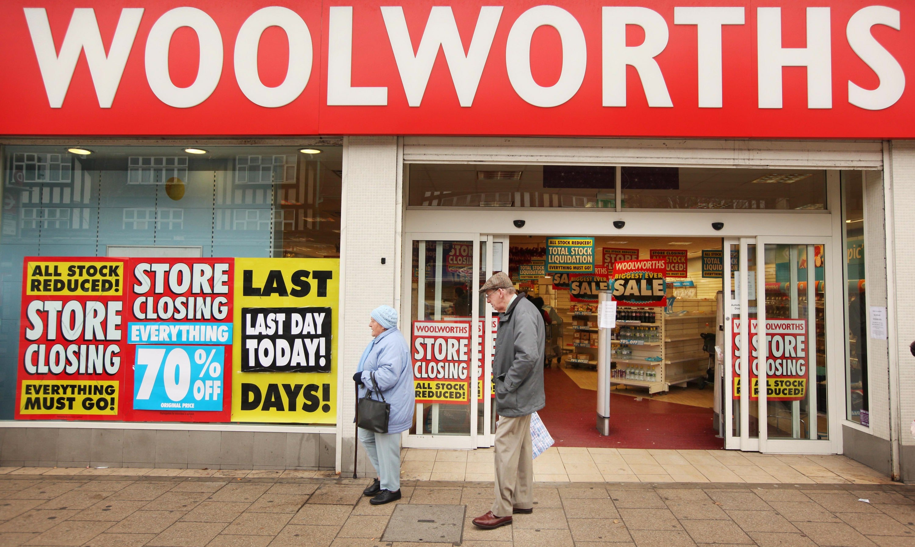 Shoppers pass a Woolworths shop on its last day of trading on December 27, 2008 in New Malden, London