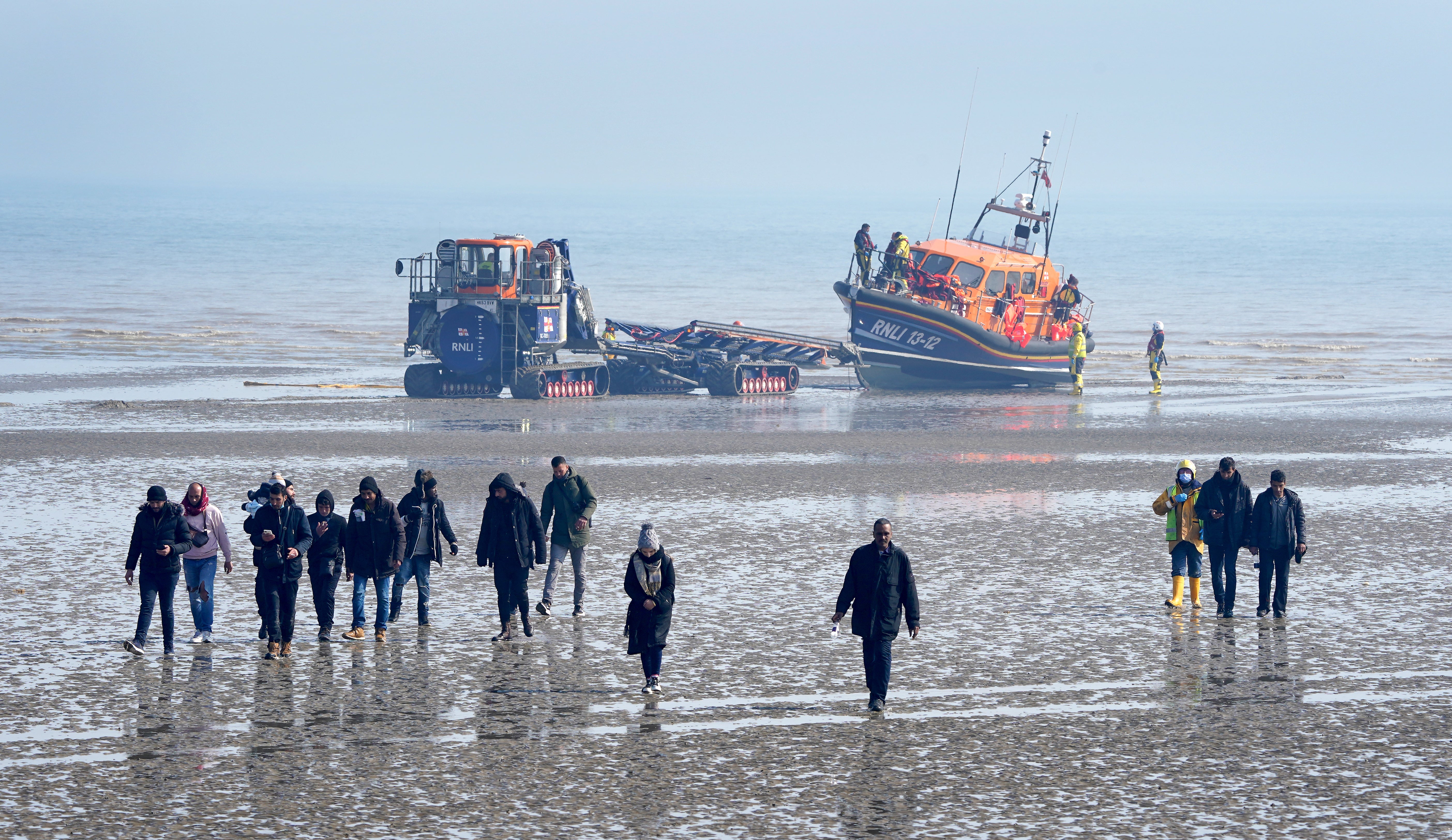 A group of people thought to be migrants are are guided up the beach after being brought in to Dungeness, Kent (Gareth Fuller/PA)