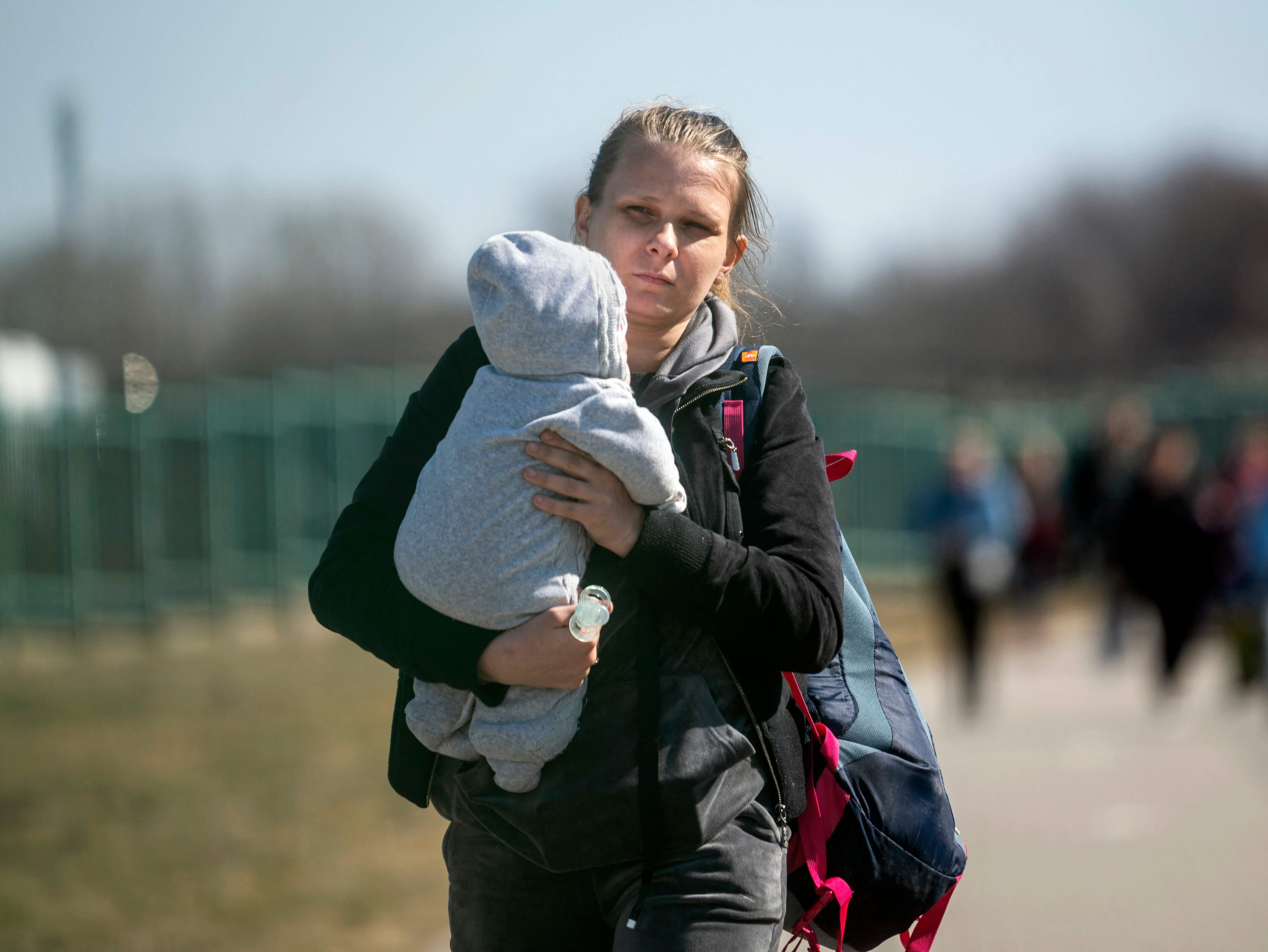 A woman carries a child across the Ukrainian-Polish border in Medyka, southeastern Poland