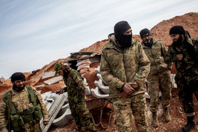 <p>Abu Taim al Mourad (wearing a balaclava), a 45-year-old former nurse from Hama turned fighter is seen on the frontline near the regime-controlled town of Saraqib</p>