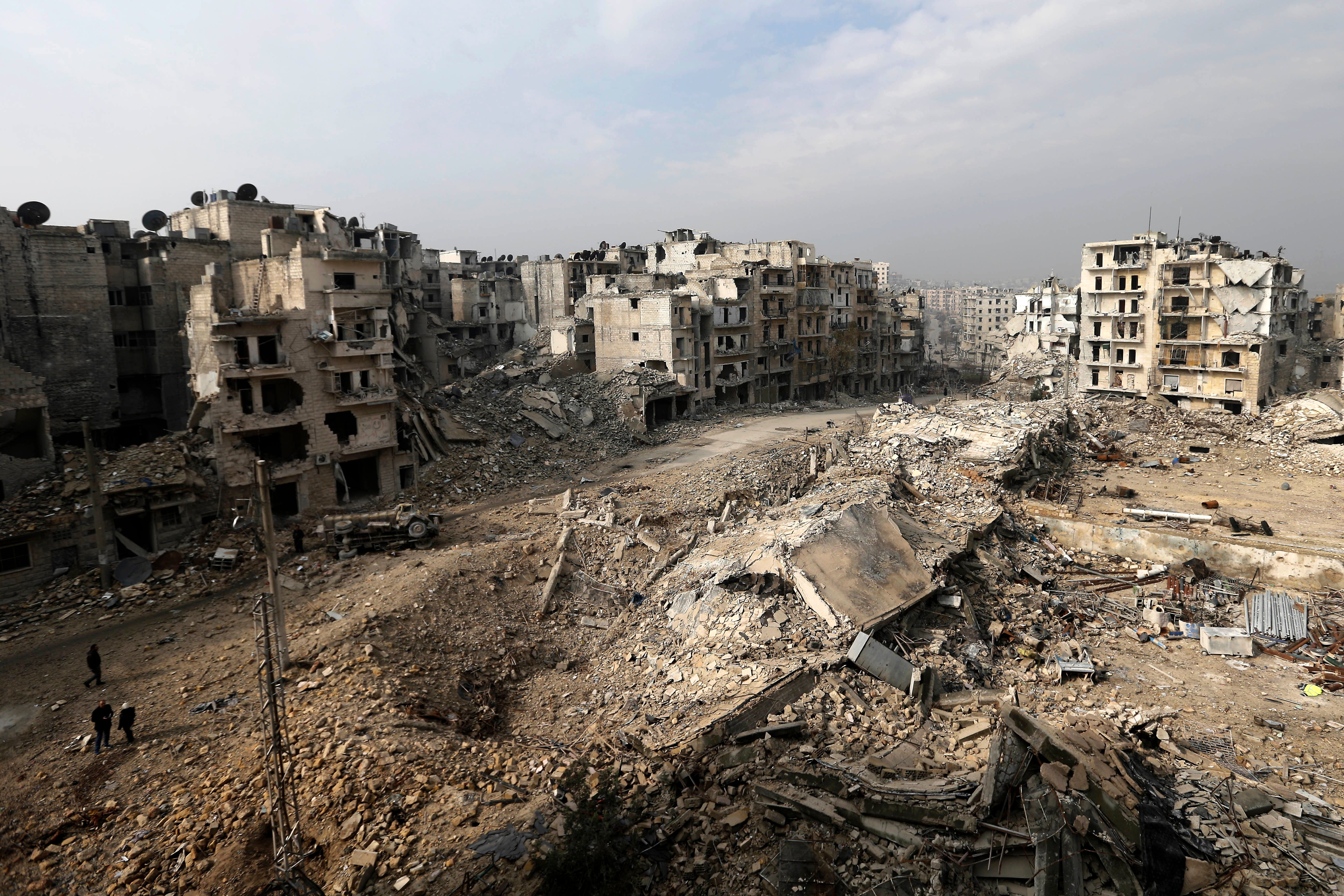 People walk through mounds of rubble which used to be high rise apartment buildings in the once rebel-held Ansari neighborhood in eastern Aleppo, in 2017