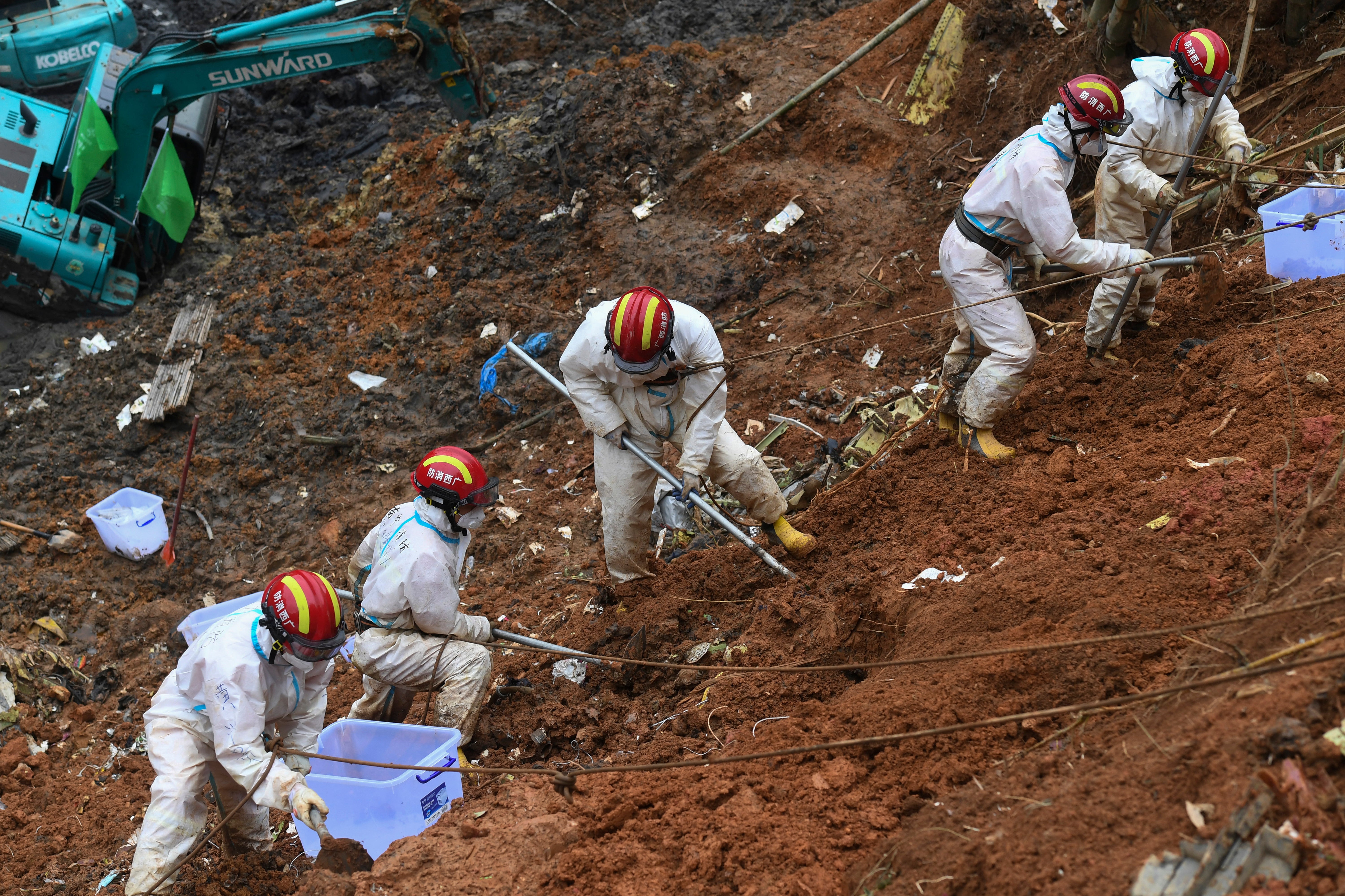 Workers excavate soil as part of the search and rescue operation at the crash site