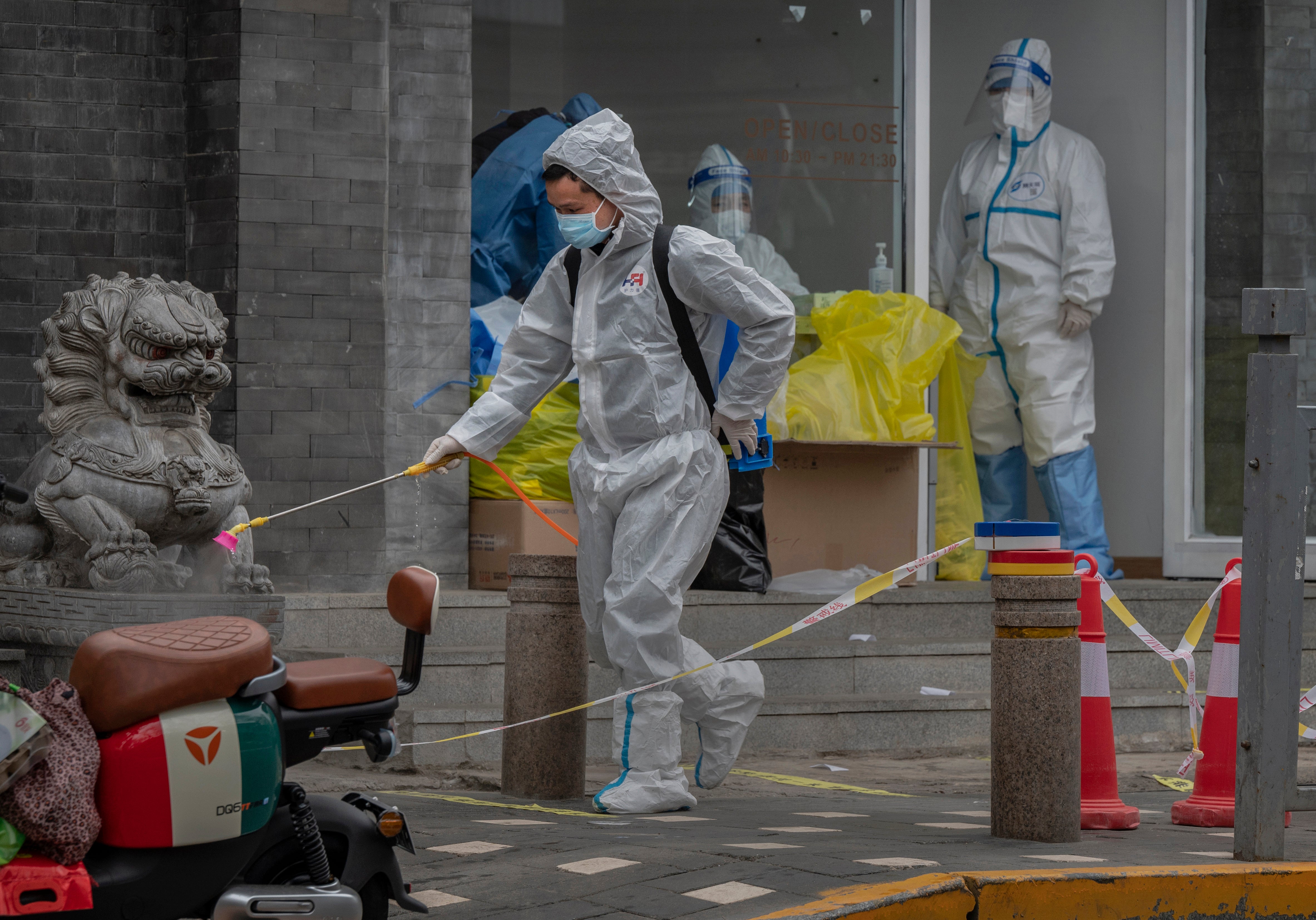 A health worker wears a protective suit as he disinfects an area around a Covid testing site