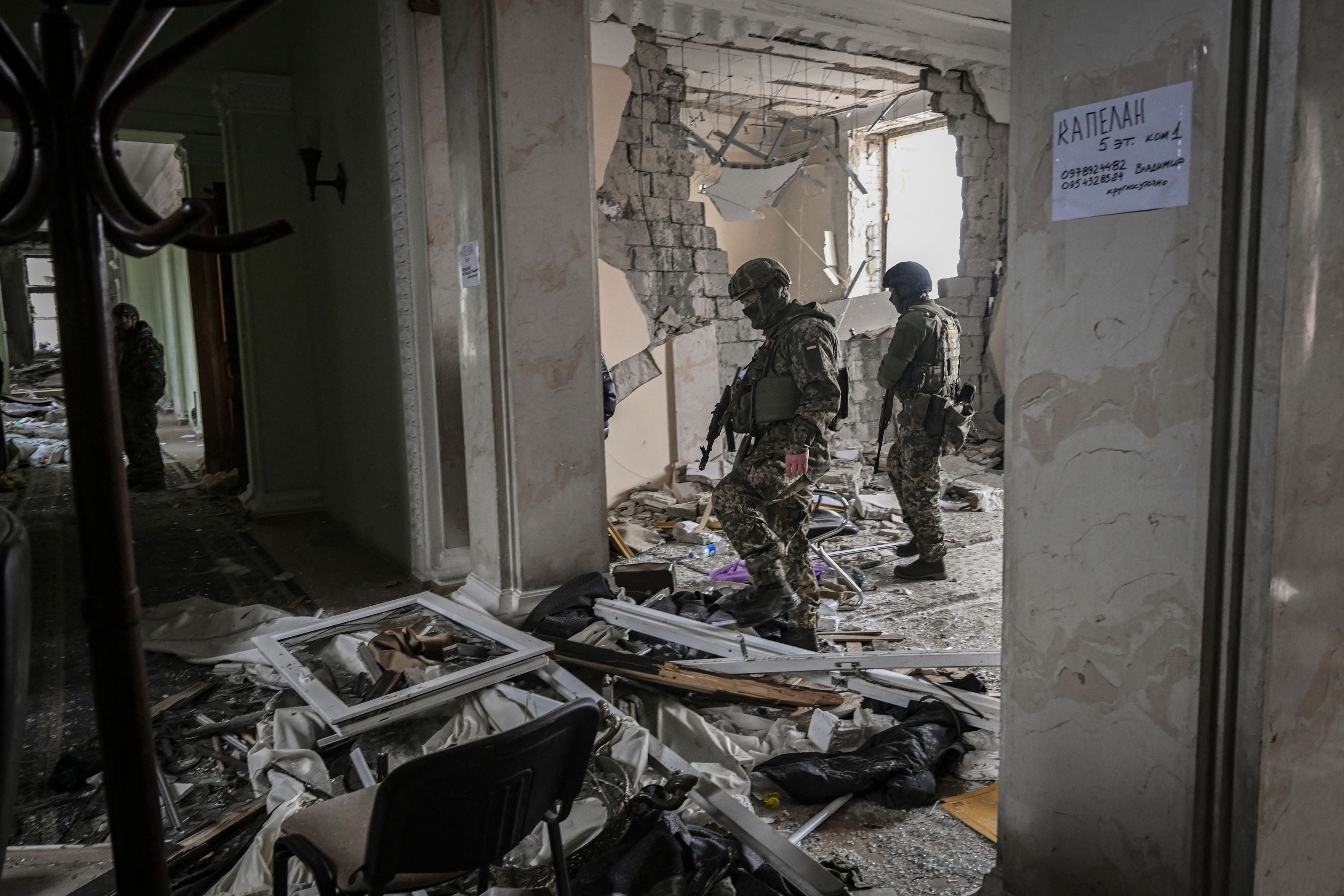 Ukranian soldiers walk inside the destroyed regional headquarters of Kharkiv