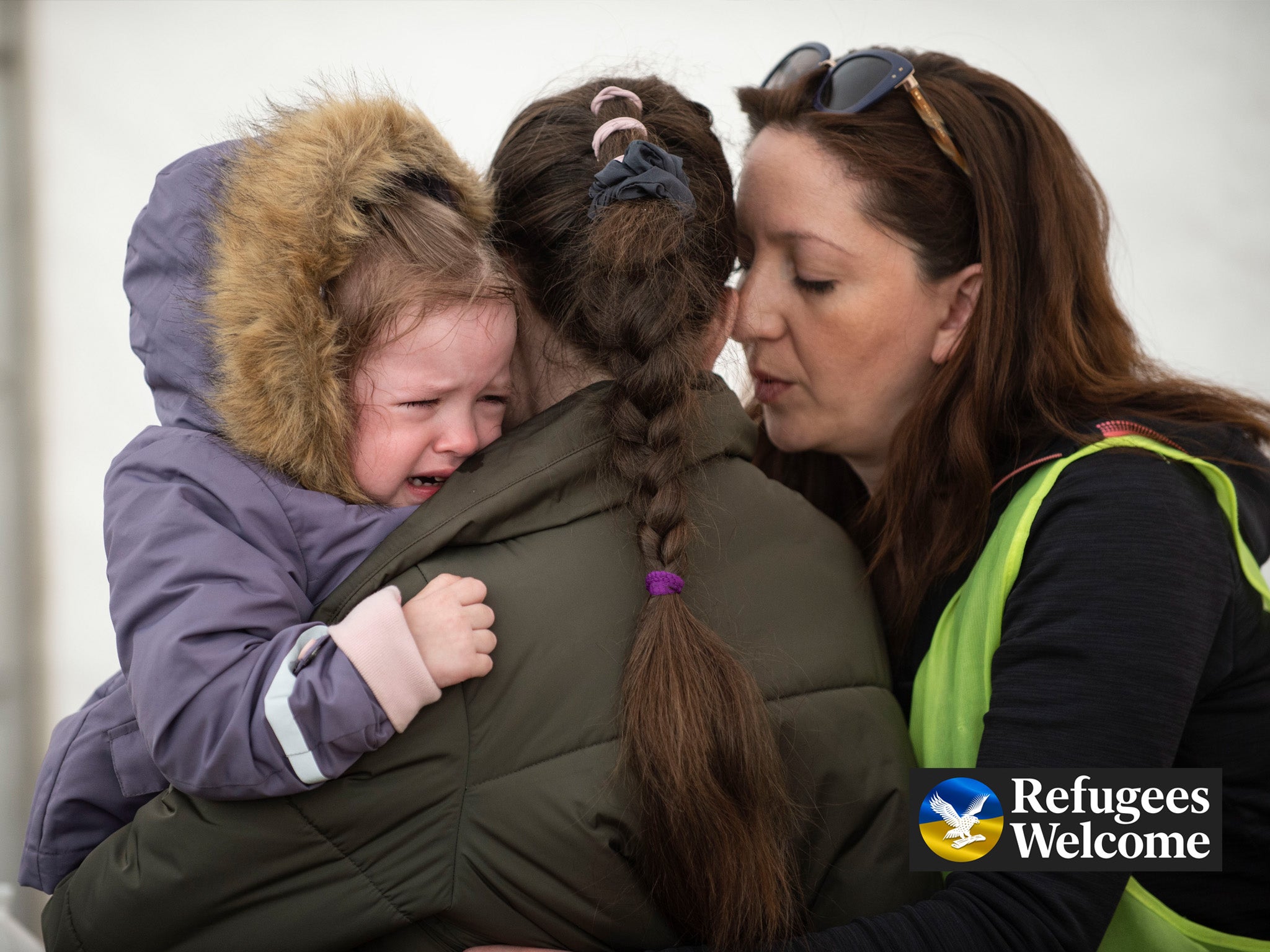 A Ukrainian mother holds her daughter as they weep at Záhony train station on the Hungarian/Ukrainian border as a volunteer attempts to console them