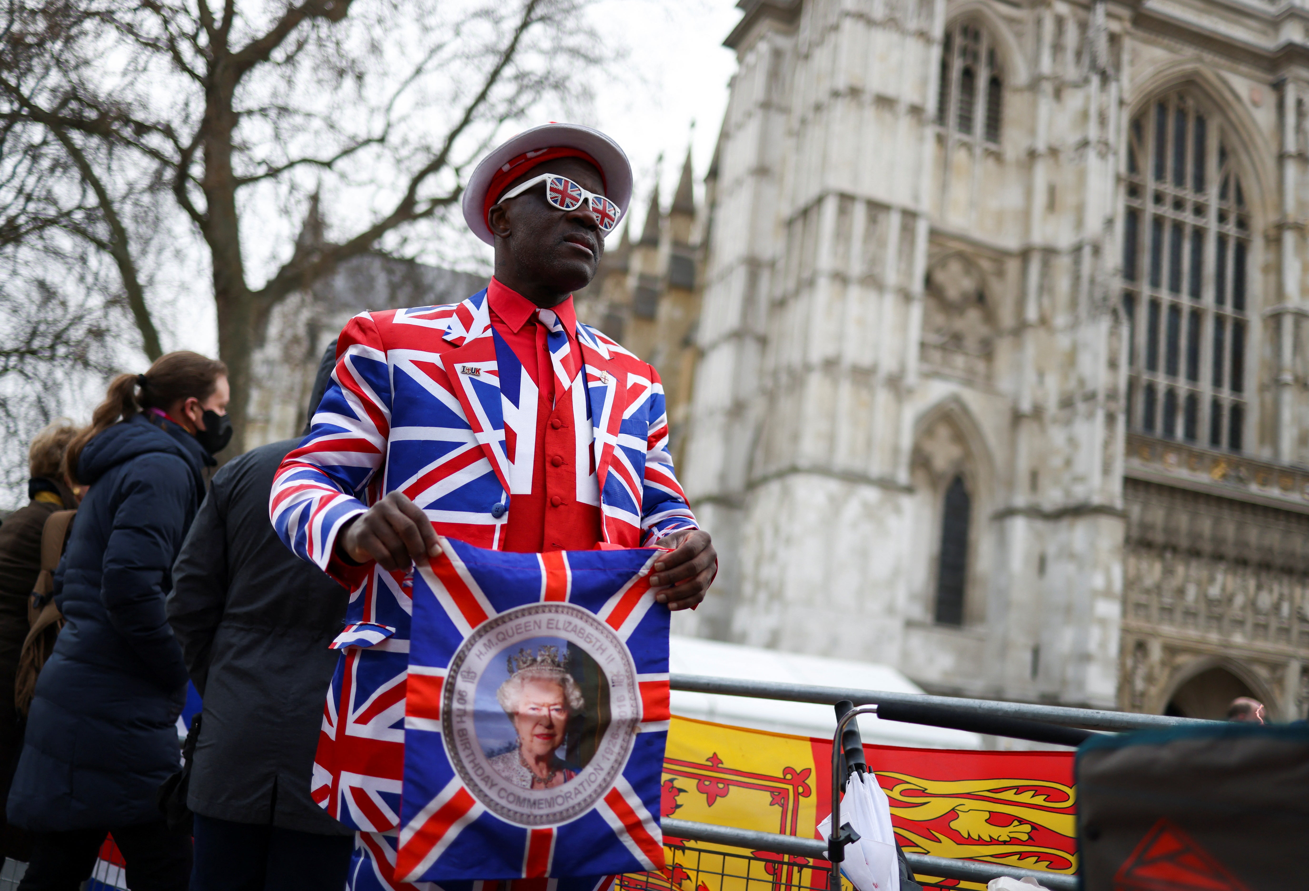 A royal enthusiast, dressed in a Union Jack flag suit, holds a bag with Queen Elizabeth's portrait before the service of thanksgiving for late Prince Philip, Duke of Edinburgh