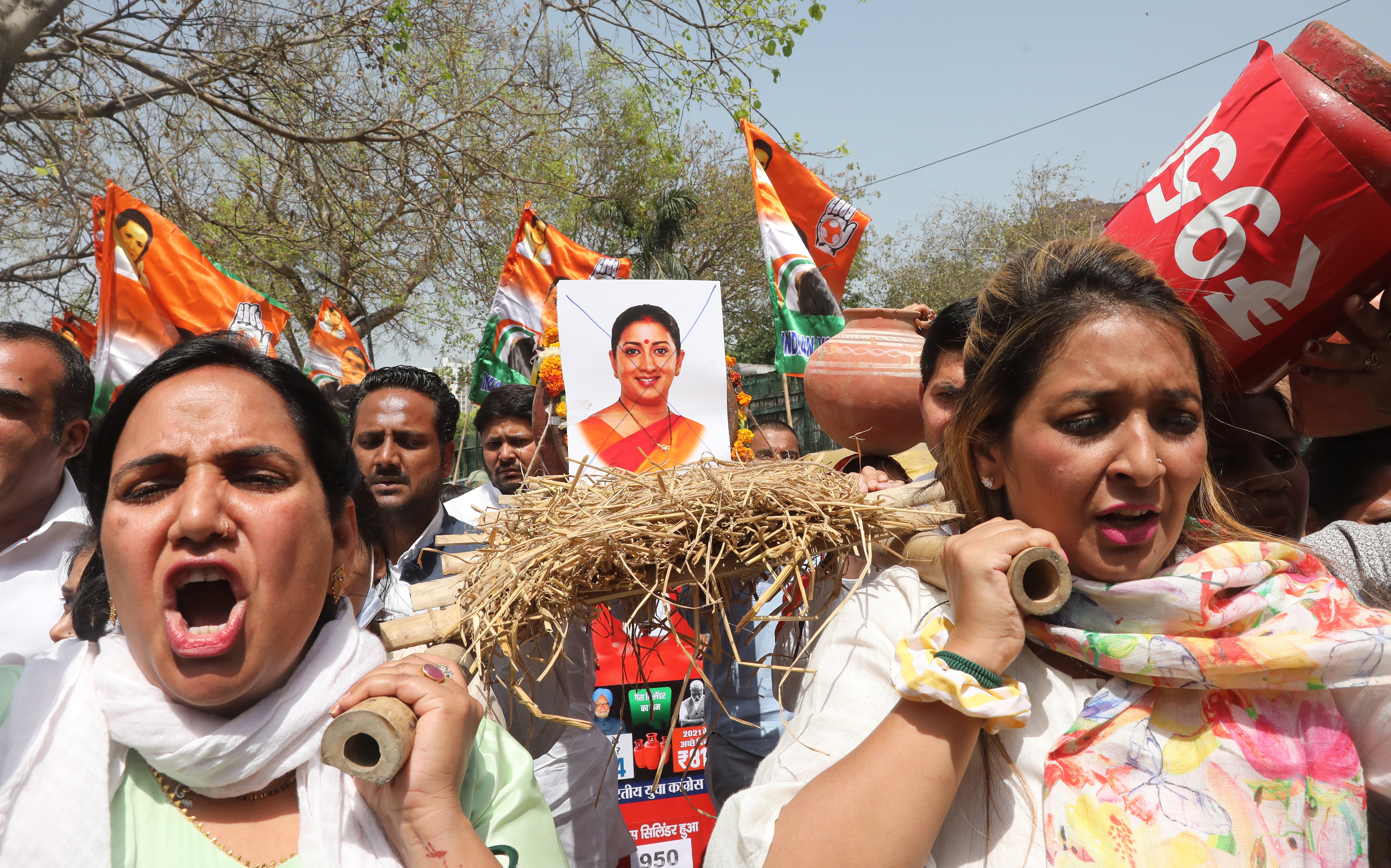 Indian Youth Congress (IYC) activists stage a mock funeral procession of a domestic gas cylinder, with the photo of Indian minister for women and child development Smriti Irani