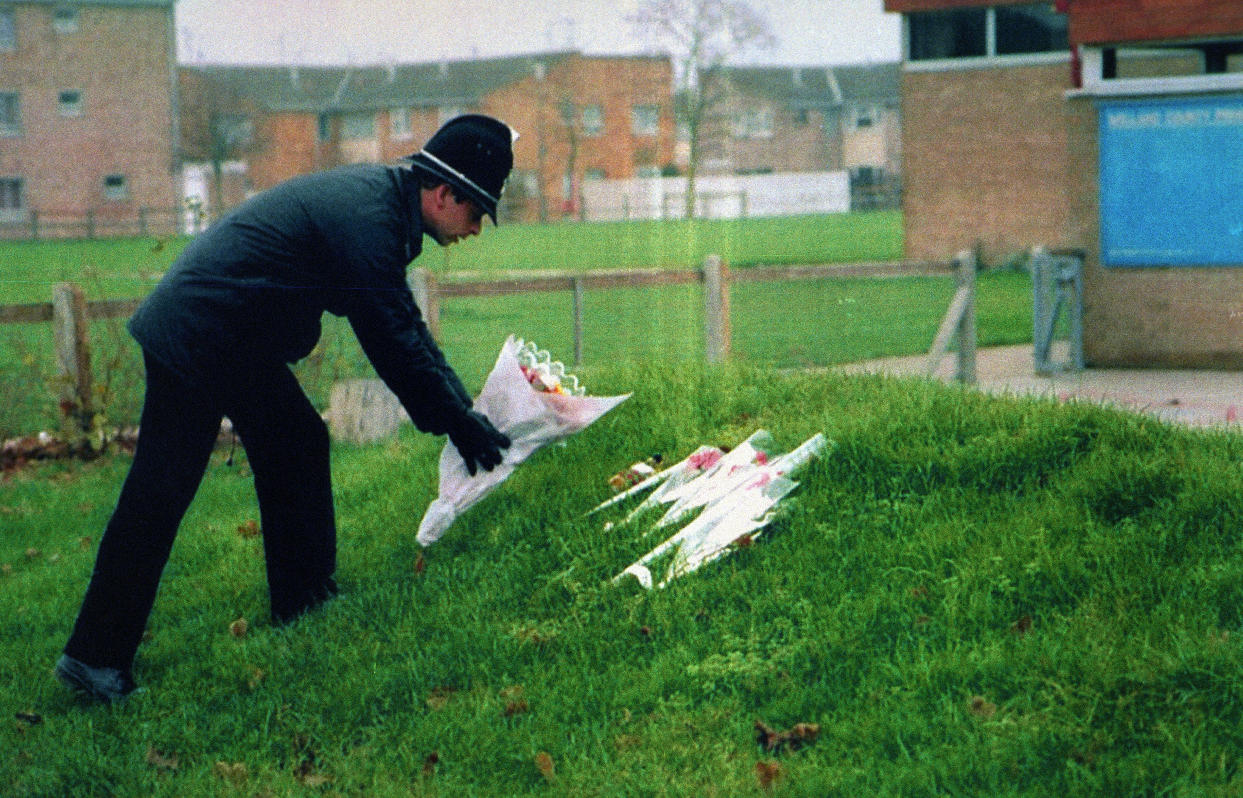 A policeman leaving flowers at Welland County Primary School in Peterborough, the school of murdered Rikki (PA)