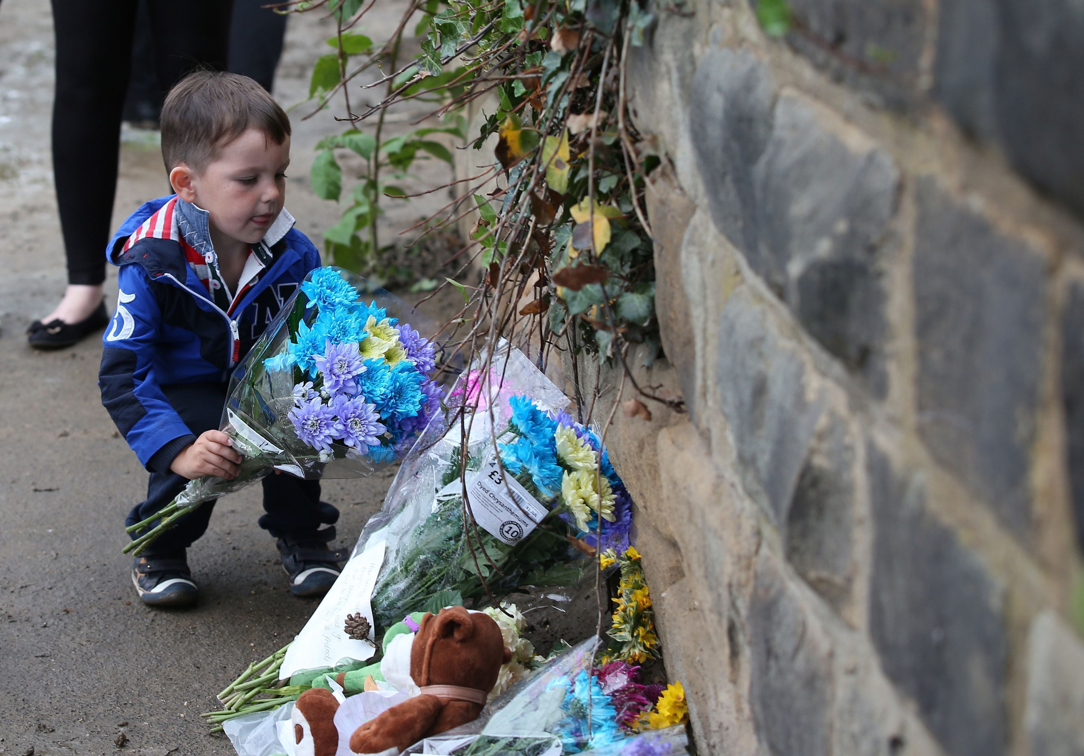 Finley Bolton, four, places flowers near the building site