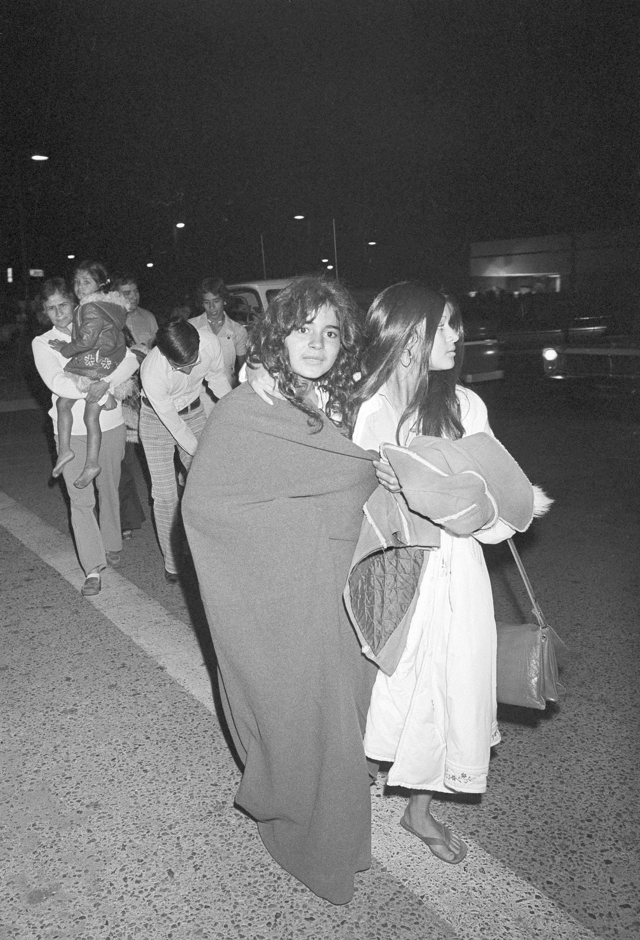 Some of the rescued children walk to a car clad in blankets after their ordeal