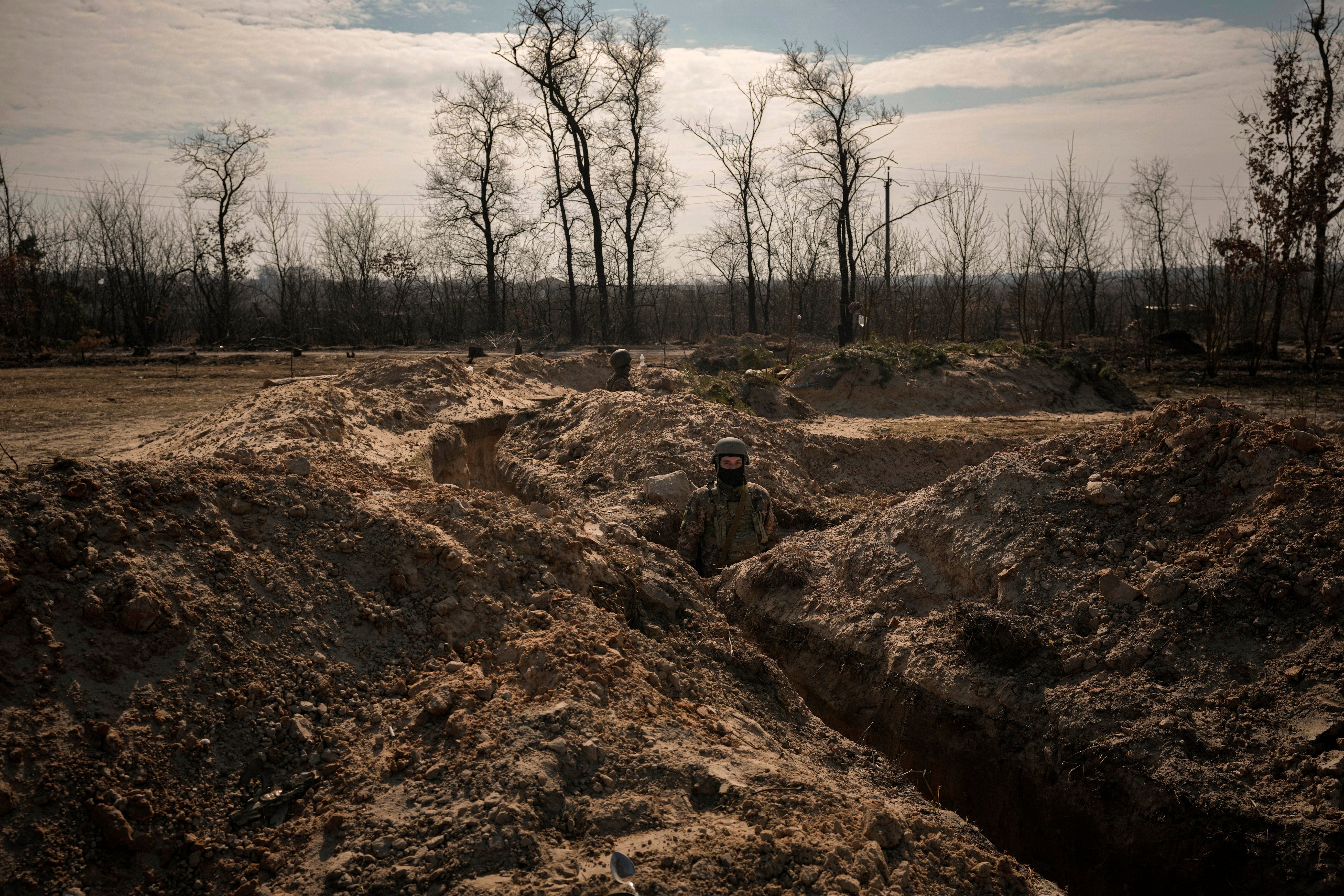 Ukrainian servicemen stand in trenches at a position north of the capital Kyiv,