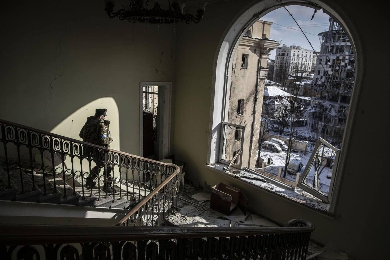 A resident walks down the stairs of a damaged building