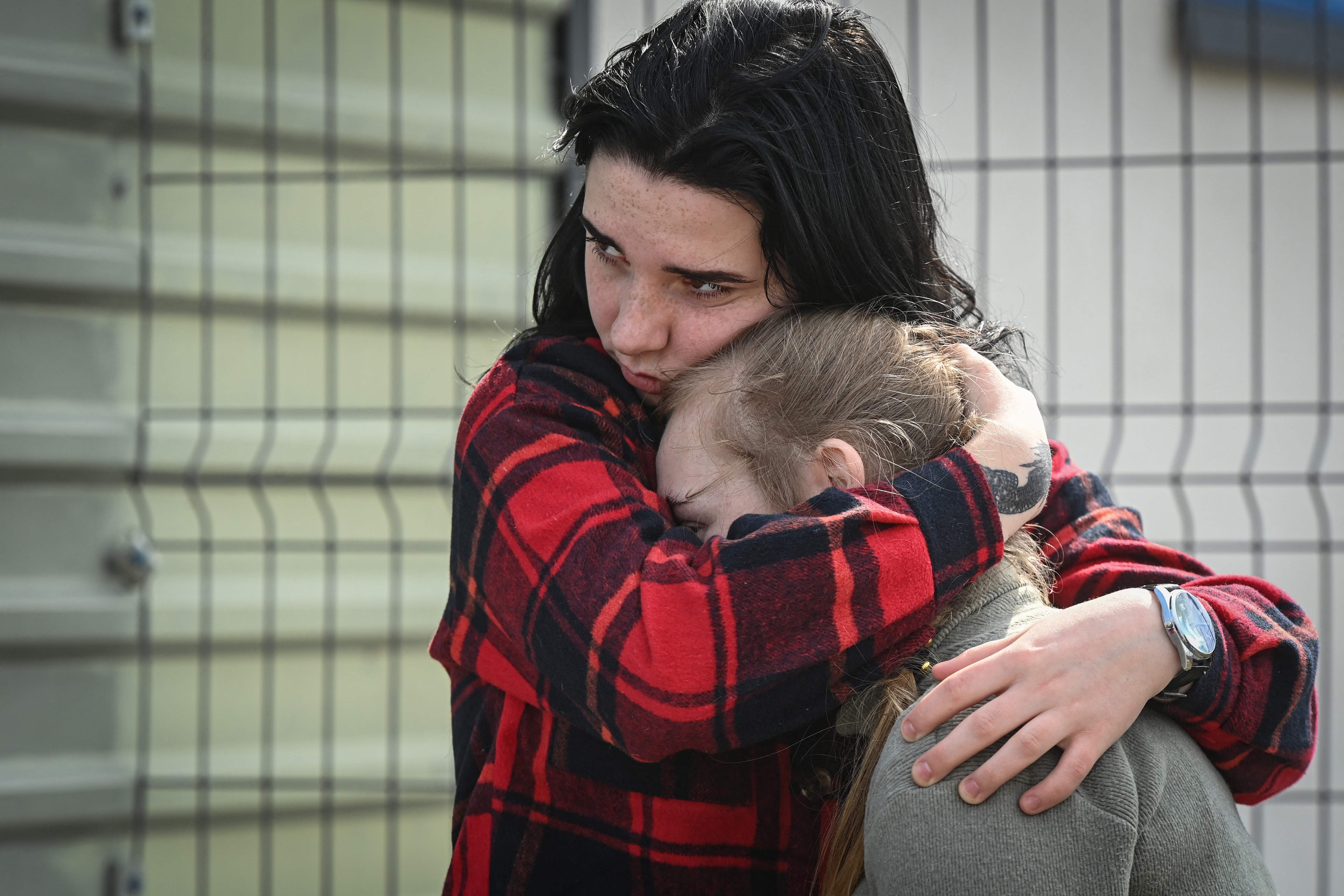 Ukrainians comfort each other as they wait to cross the border from Ukraine to Moldova