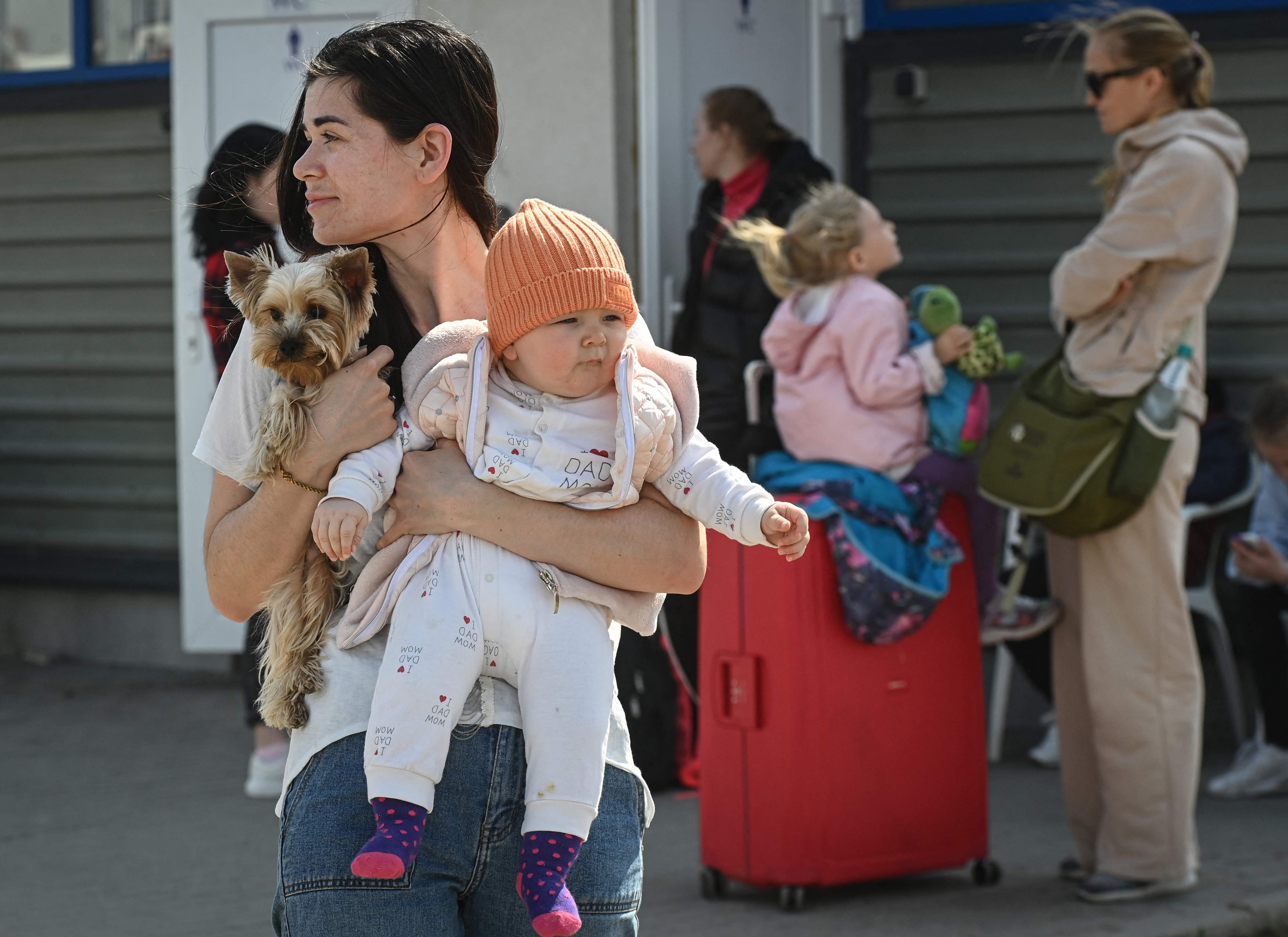 A Ukrainian refugee holds her baby and dog as she waits for a bus at a crossing point between Ukraine and Moldova