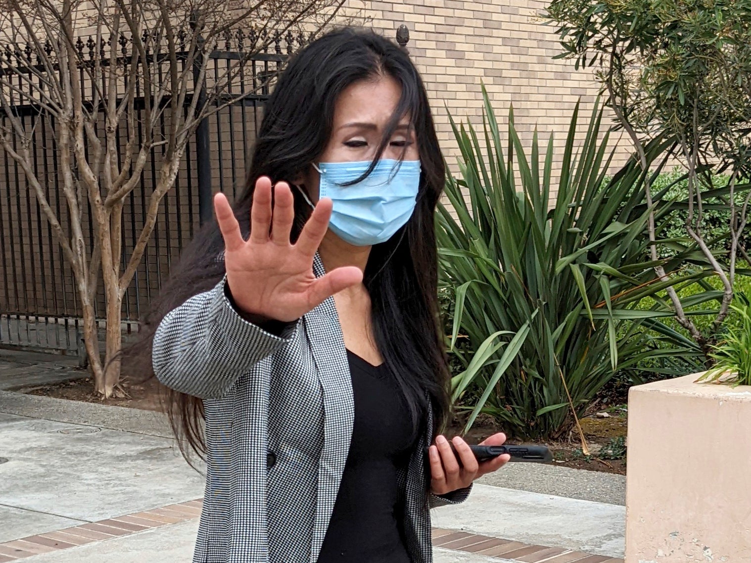 Julie Lee Choi waves off reporters outside Santa Clara Superior Court in San Jose, Calif., on Tuesday, March 29, 2022