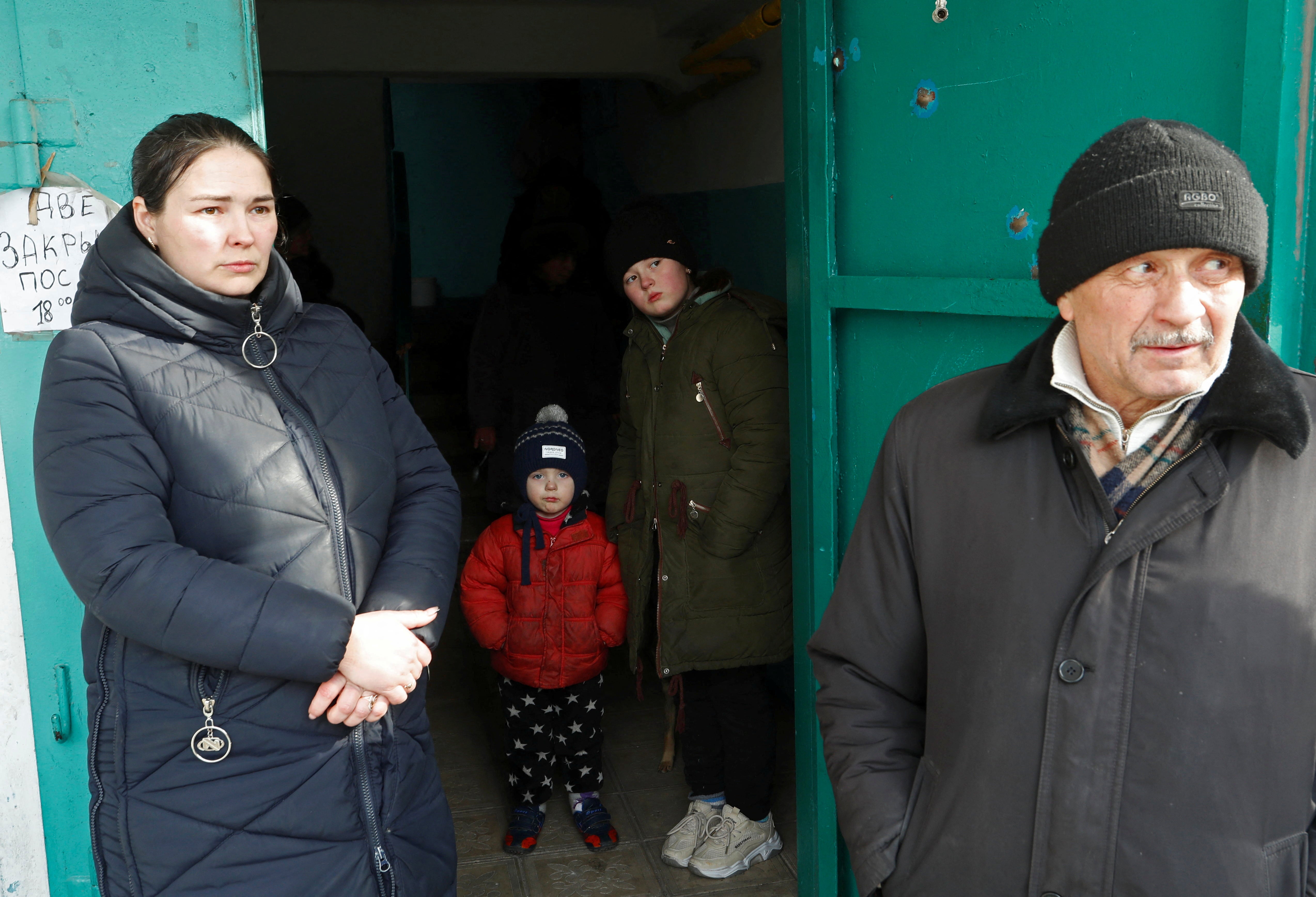 Local residents gather at the entrance of an apartment building during Ukraine-Russia conflict in the besieged southern port city of Mariupol