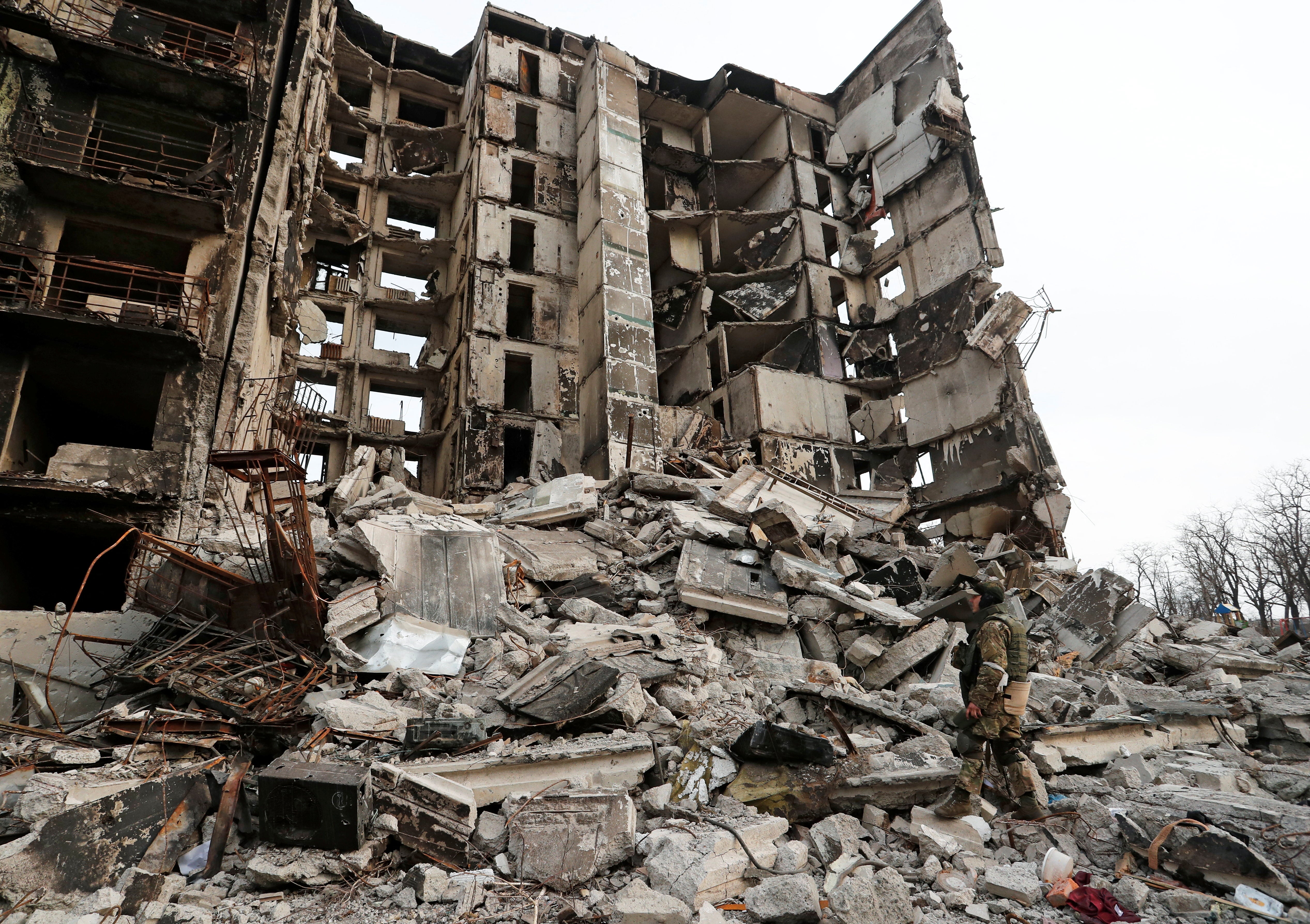 A service member of pro-Russian troops stands on the ruins of an apartment building destroyed during Ukraine-Russia conflict in the besieged southern port city of Mariupol, Ukraine March 30, 2022. REUTERS/Alexander Ermochenko