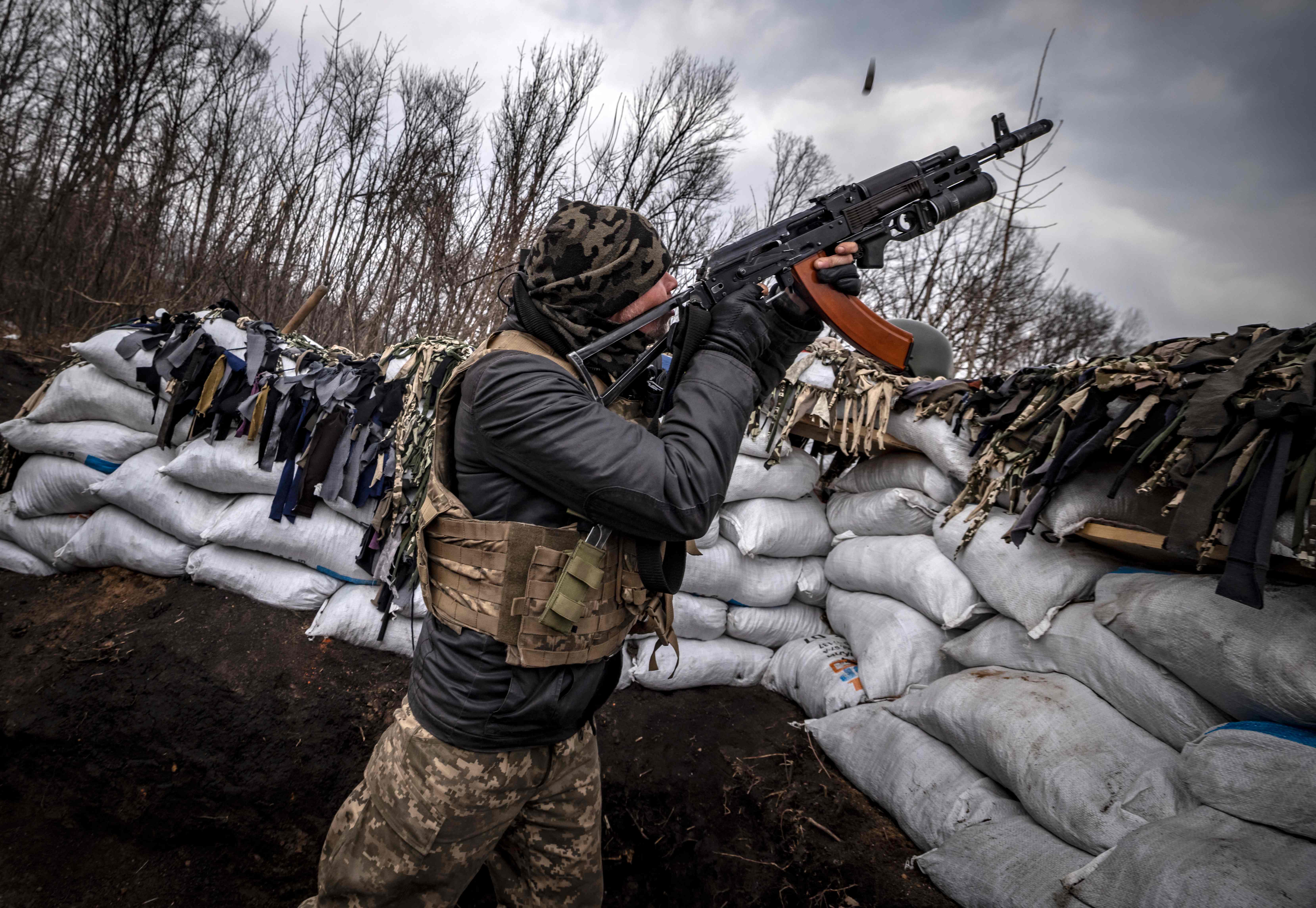 A Ukrainian serviceman shoots at a Russian drone with an assault rifle from a trench at the front line east of Kharkiv