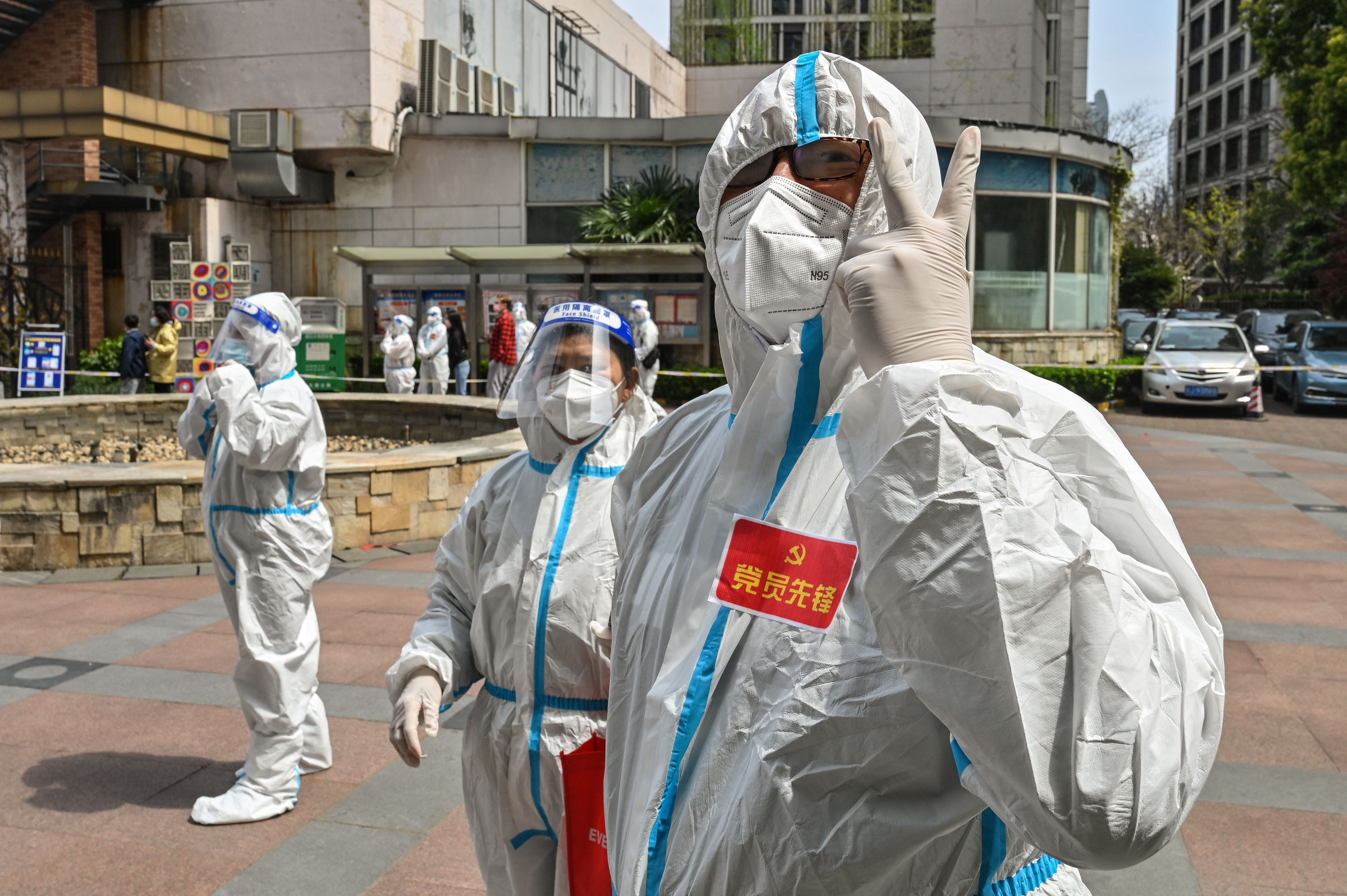 Workers and volunteers gesture in a compound where residents are tested for Covid during the second stage of a pandemic lockdown in Jing’an district in Shanghai, 1 April 2022