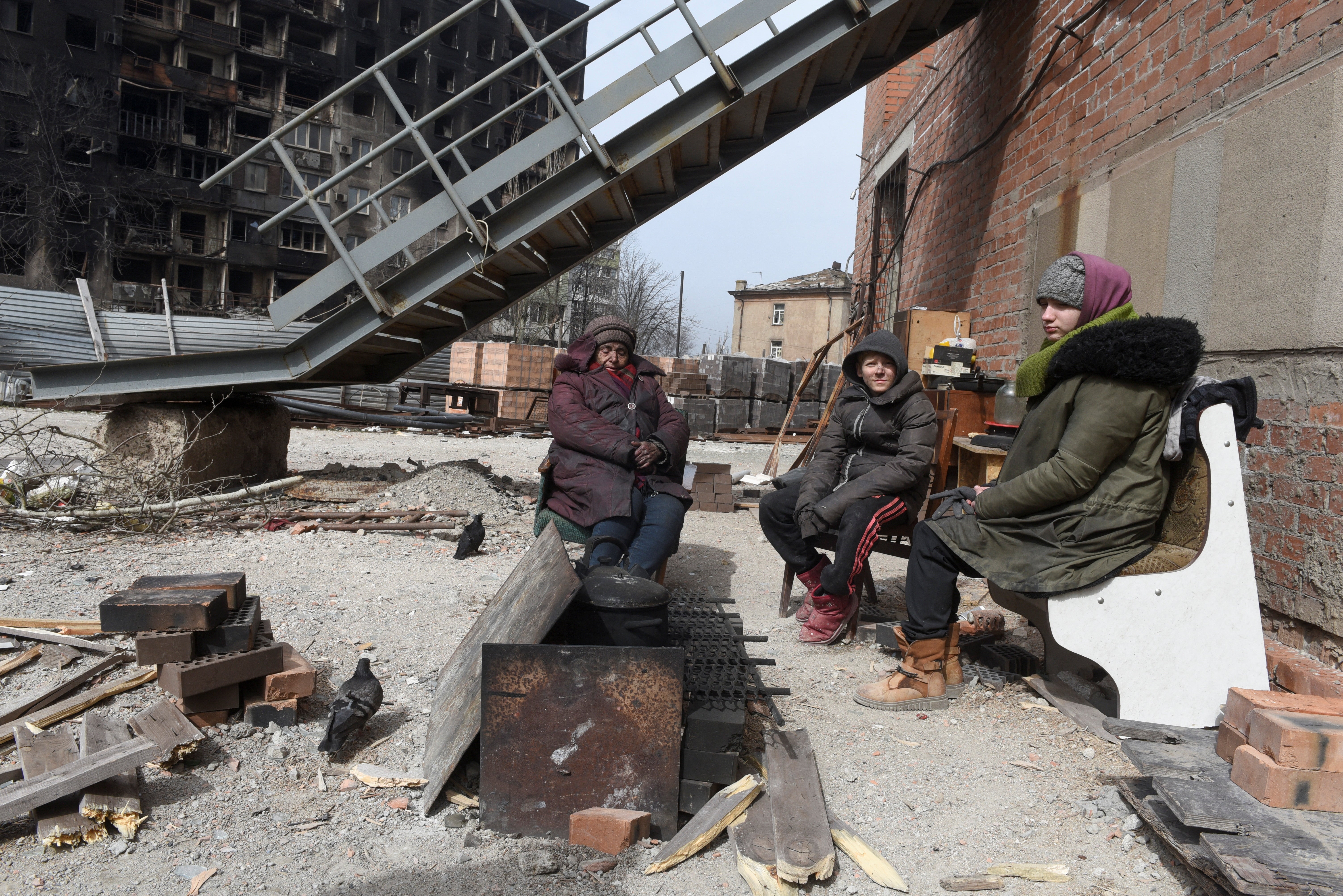 Marina Sidorenko, 83, and other local residents sit around a fire on territory of a church in Mariupol