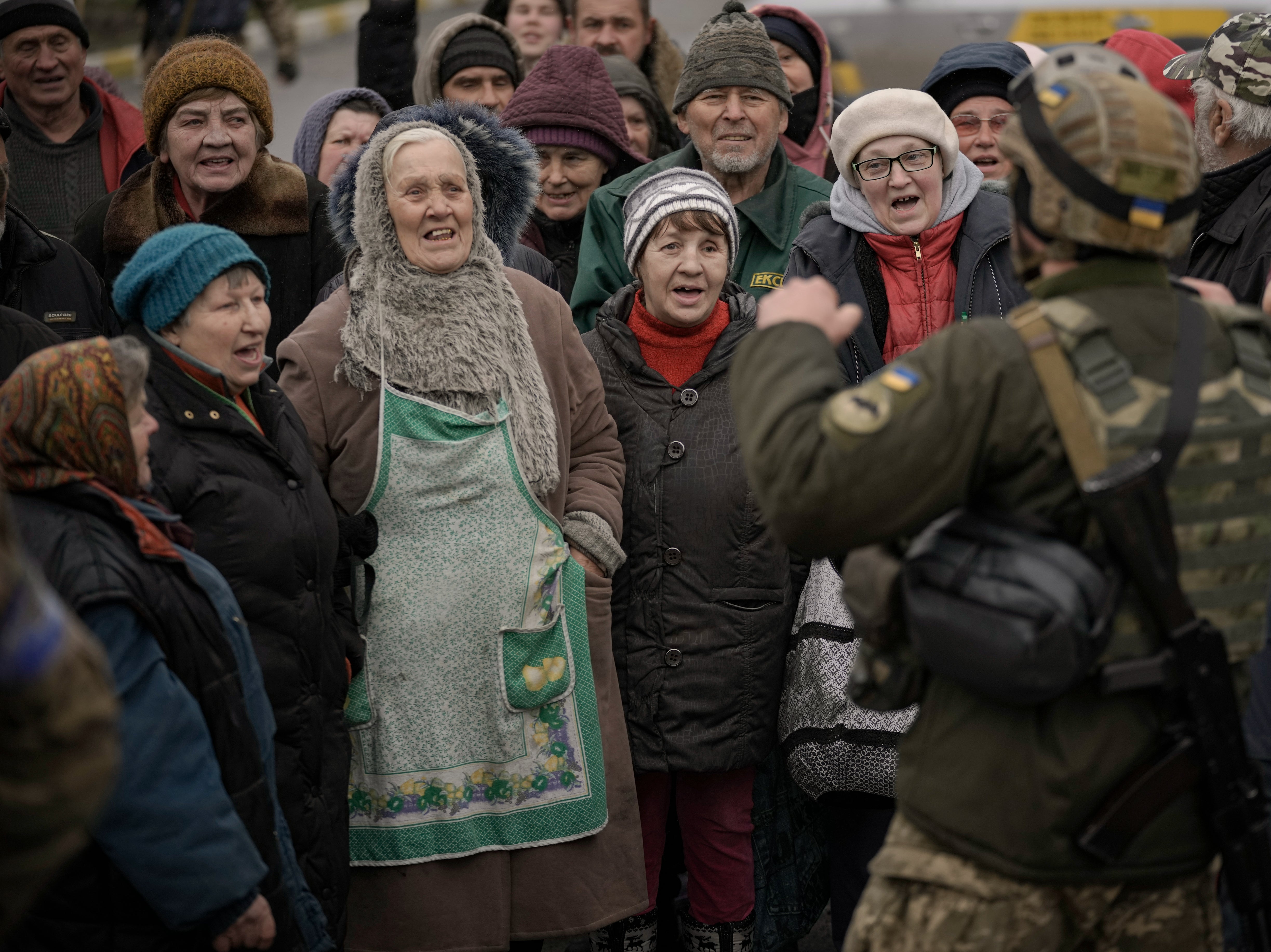 Civilians cheer along with a Ukrainian serviceman as a convoy of military and aid vehicles arrives in the formerly Russian-occupied Kyiv suburb of Bucha