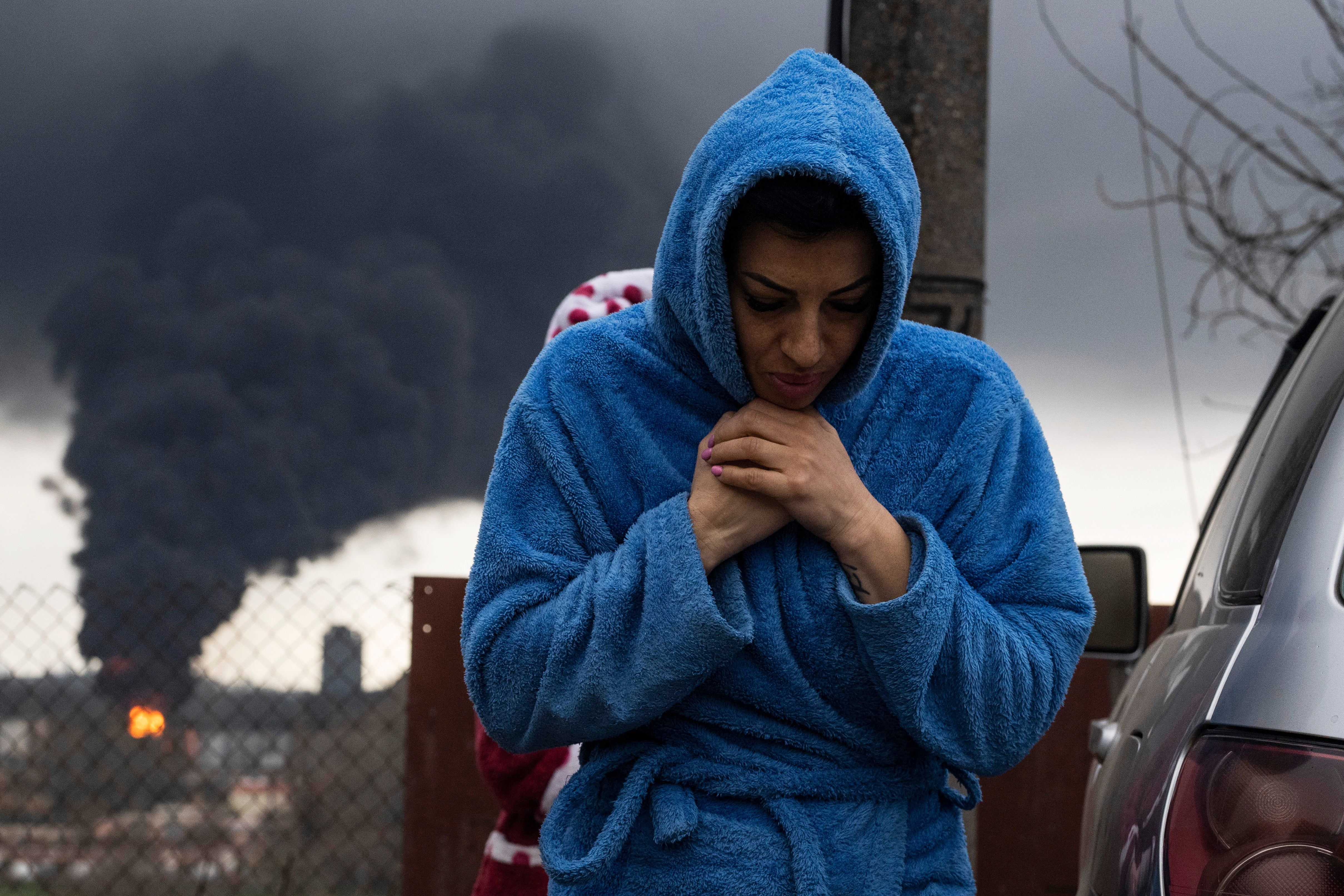 A woman in Odesa as black smoke rises above the Black Sea port following shelling