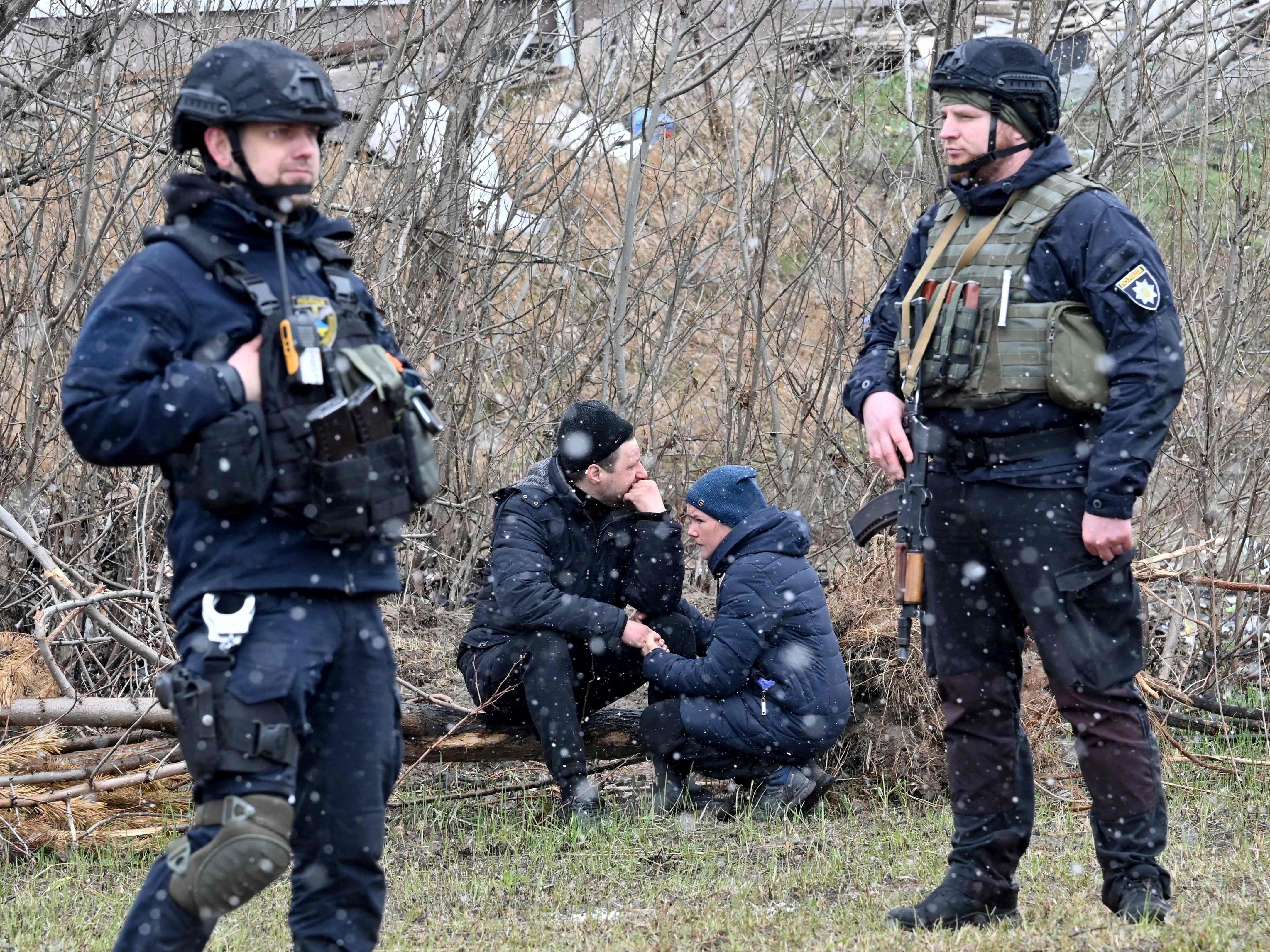 People react as they gather close to a mass grave in the Ukrainian town of Bucha