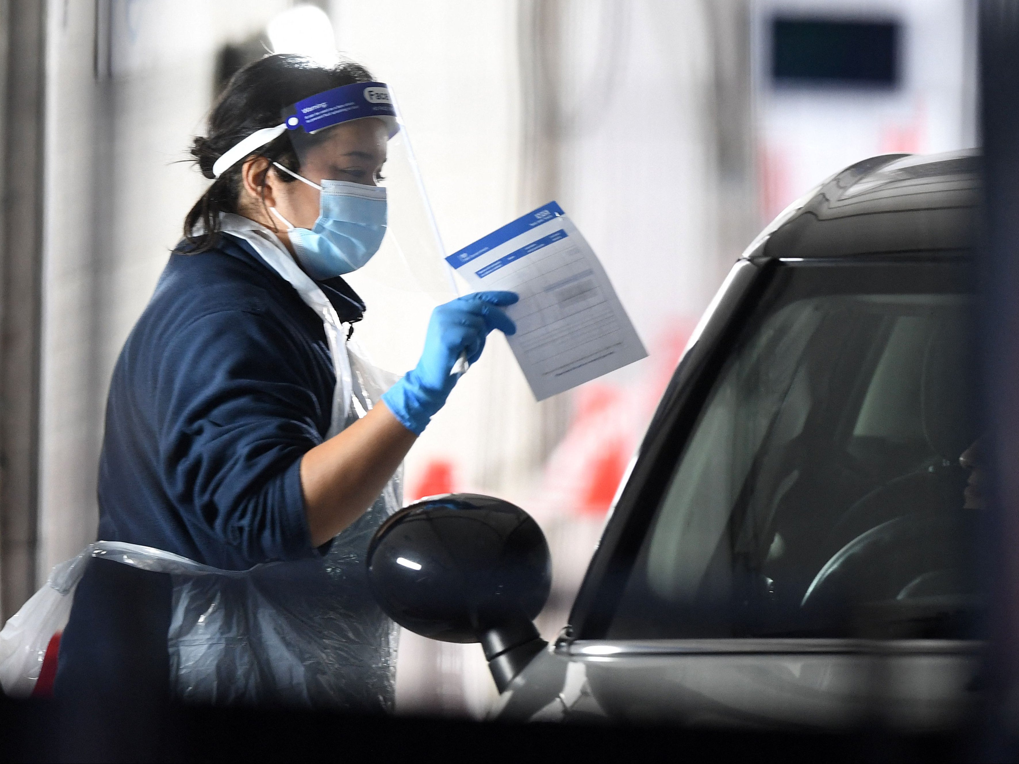 A medical worker talks to a member of the public waiting in their car to take a test for Covid