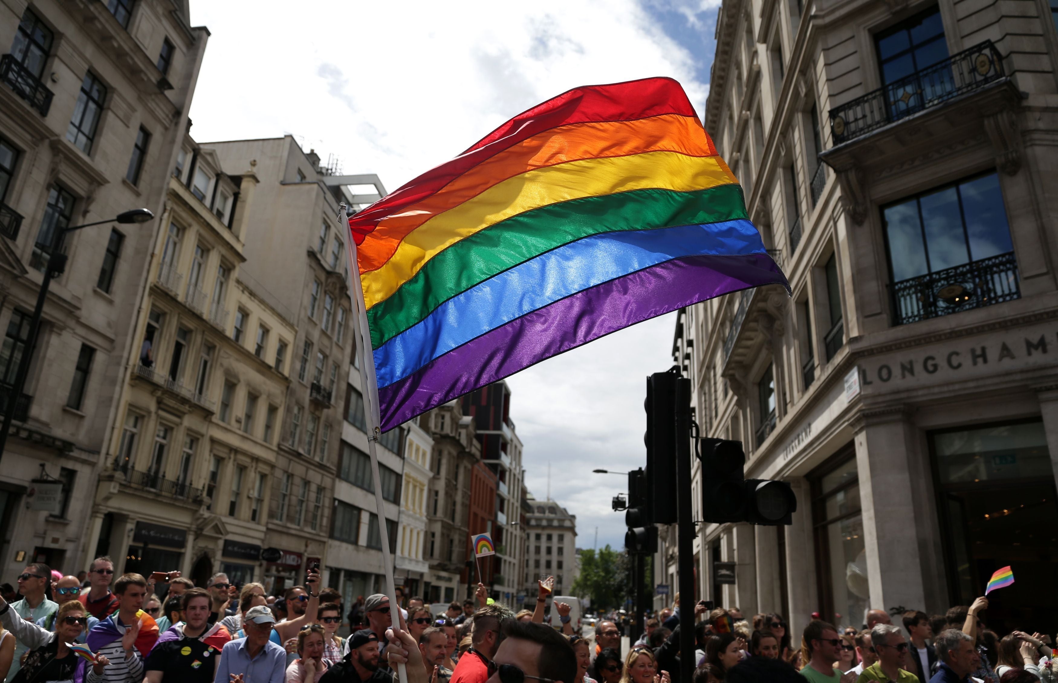 A rainbow flag is held aloft (Daniel Leal-Olivas/PA)