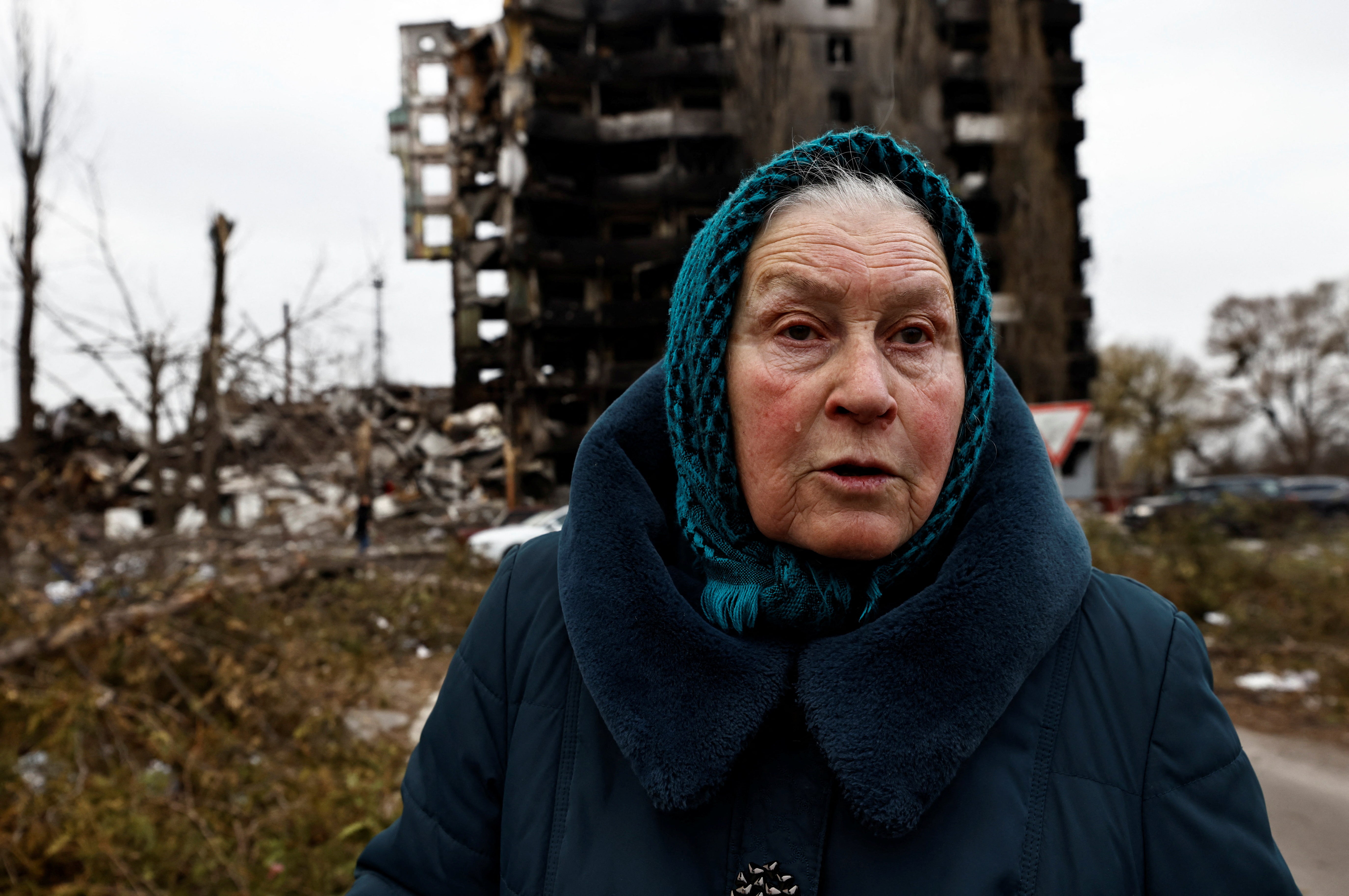 A resident stands in front of a destroyed apartment block in Borodyanka, a town near Kyiv