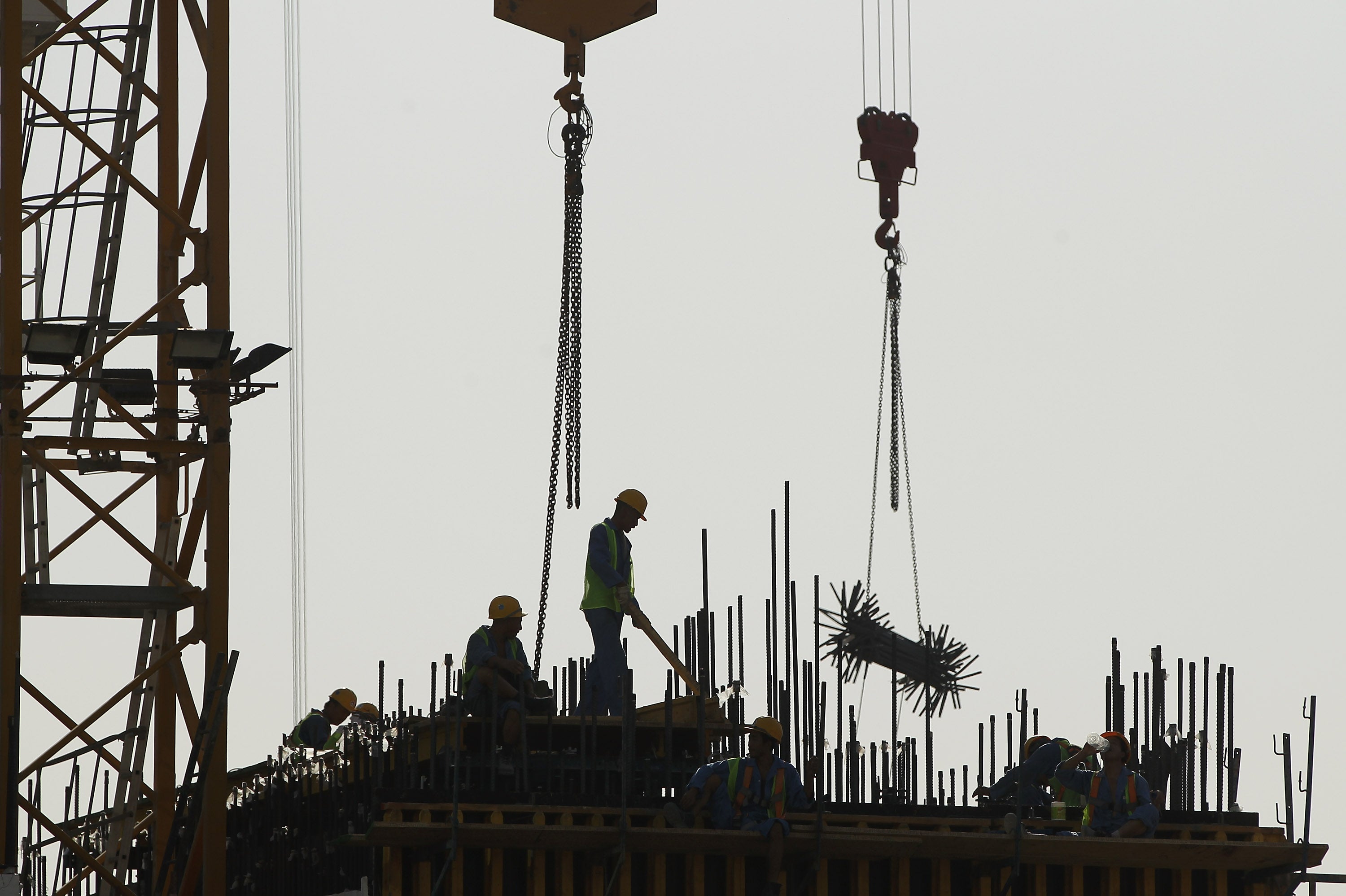 Workers stand on the construction site of a new office building in the budding new financial district in Doha, Qatar